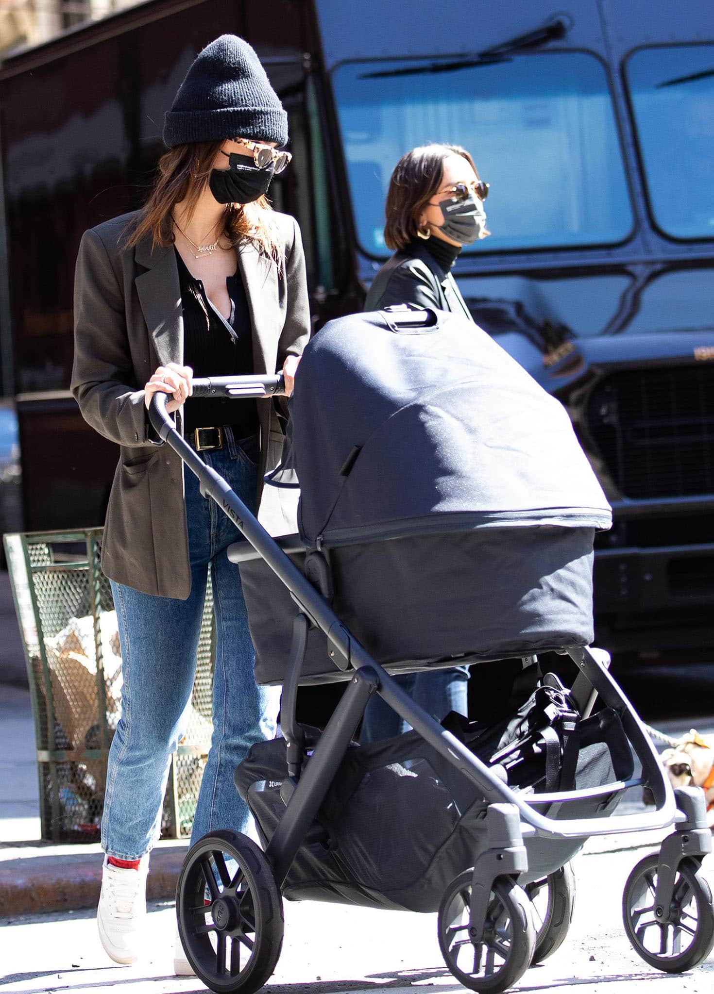 Emily Ratajkowski looks chic in a cleavage-baring black top with straight-leg jeans, brown blazer, and red socks