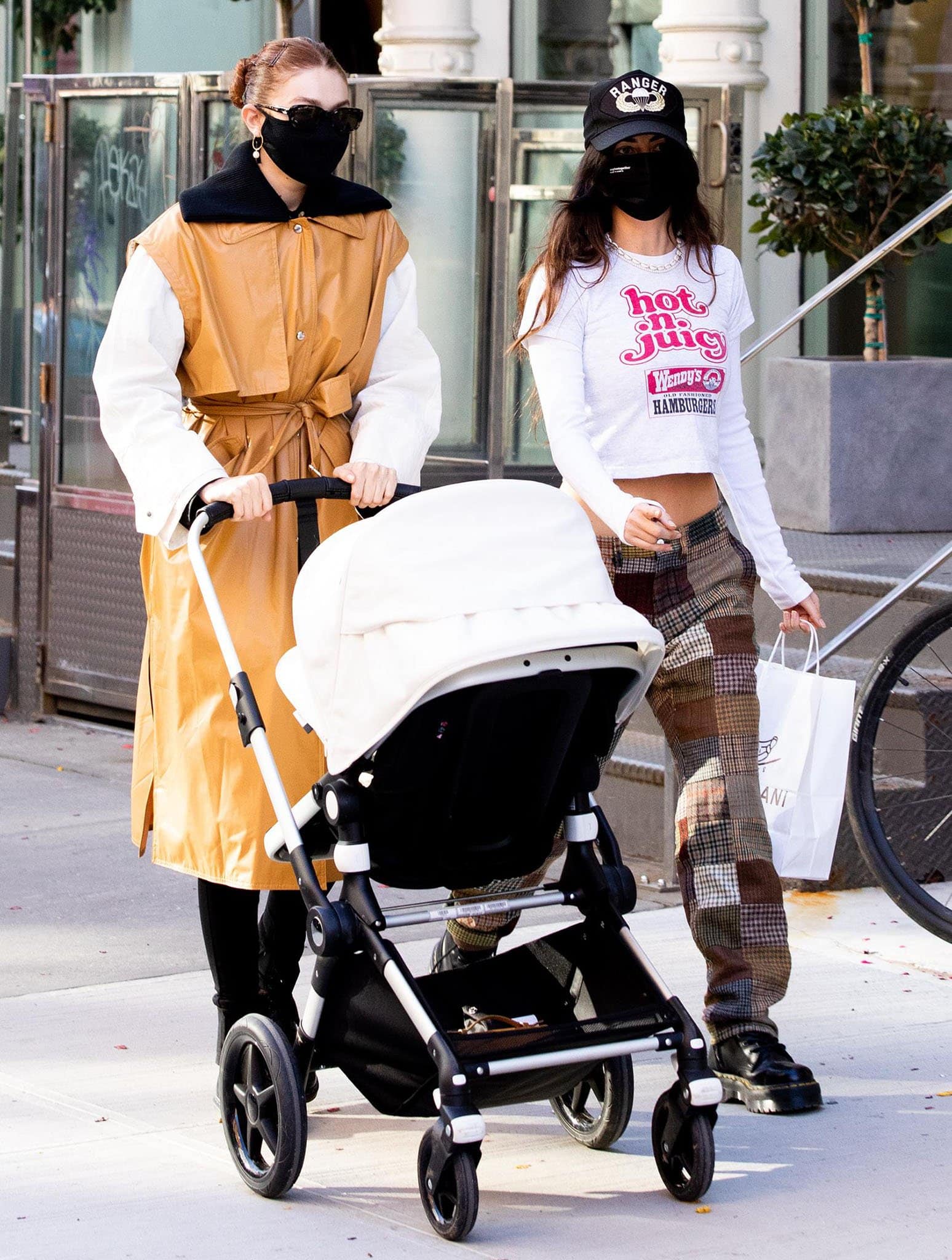 Gigi Hadid paired a statement Moncler Genius trench coat with classic Dr. Martens 1460 boots as she strolled through SoHo with daughter Khai and friend Leah McCarthy on March 22, 2021