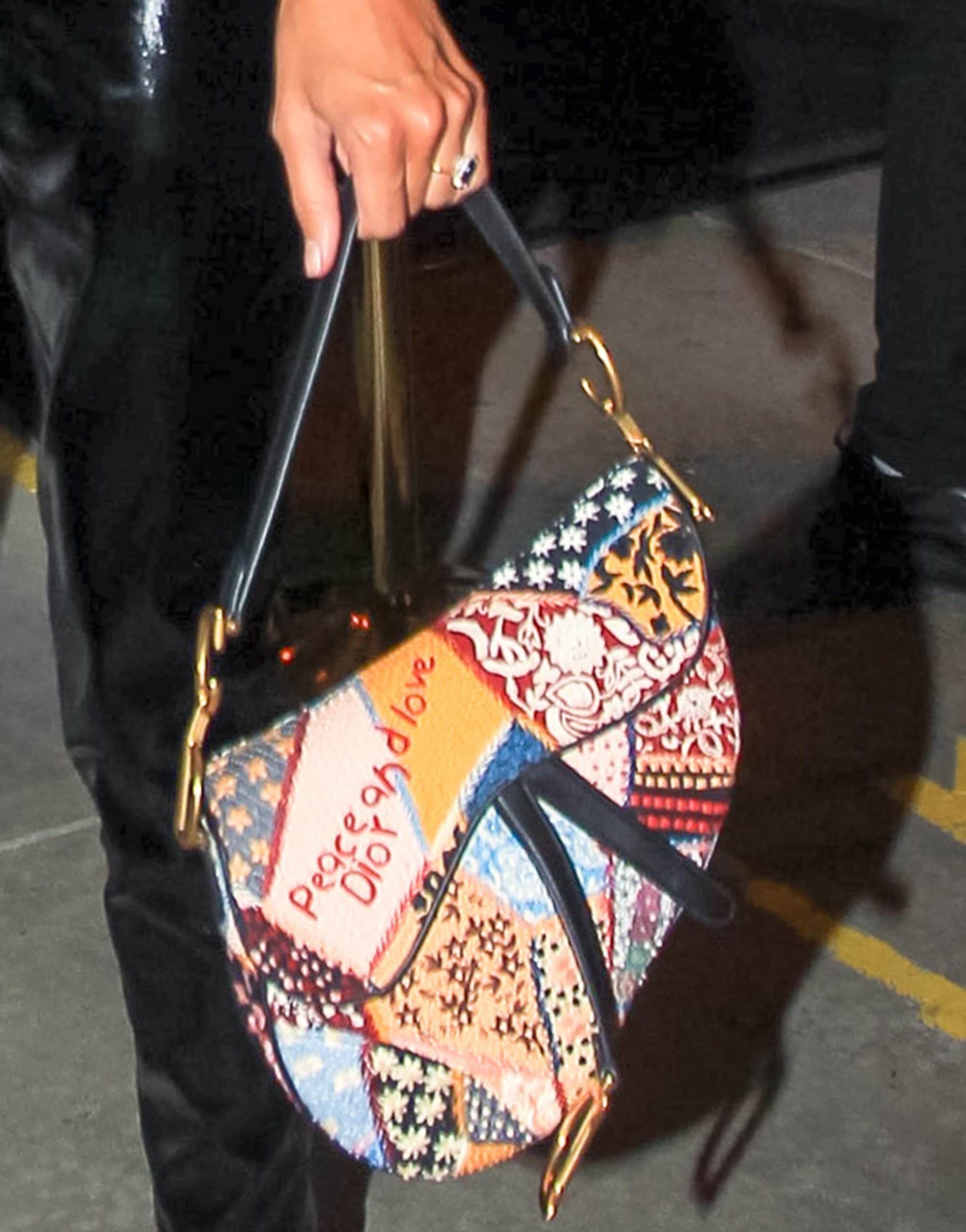 Jessica Serfaty totes a pink and multicolor embroidered and bead-embellished Christian Dior Peace and Love Saddle bag from the Fall/Winter 2018 Collection