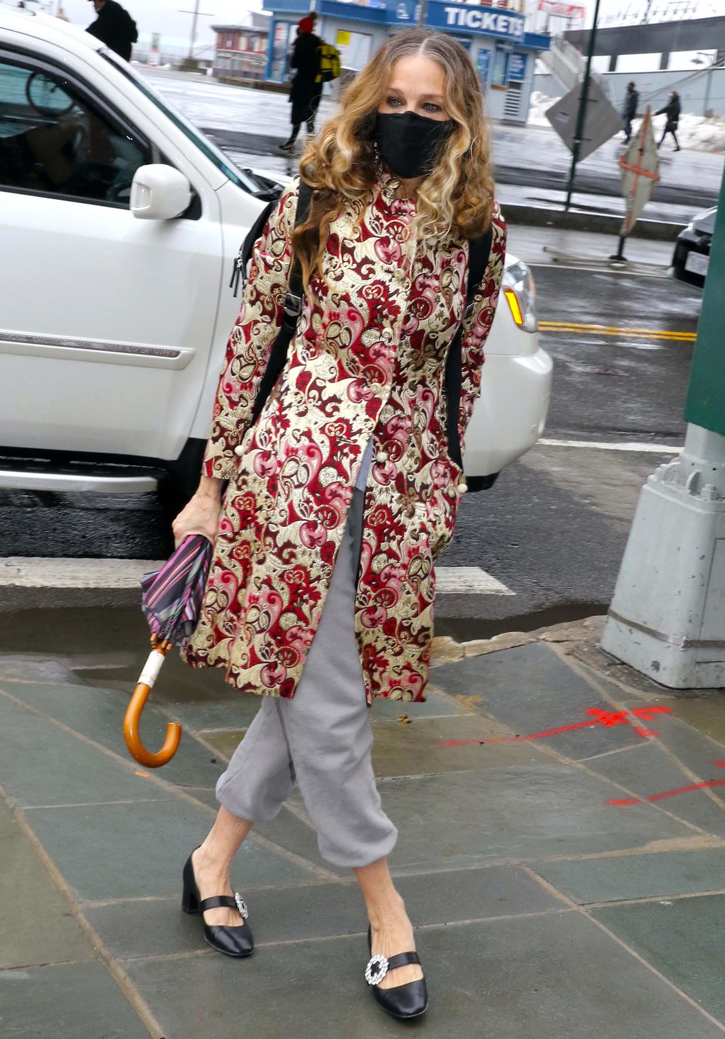 Sarah Jessica Parker visits her SJP Collection store at South Street Seaport on February 27, 2021, pairing an ornate red-and-gold embroidered coat with relaxed gray track pants and ‘Celine’ Mary Jane pumps