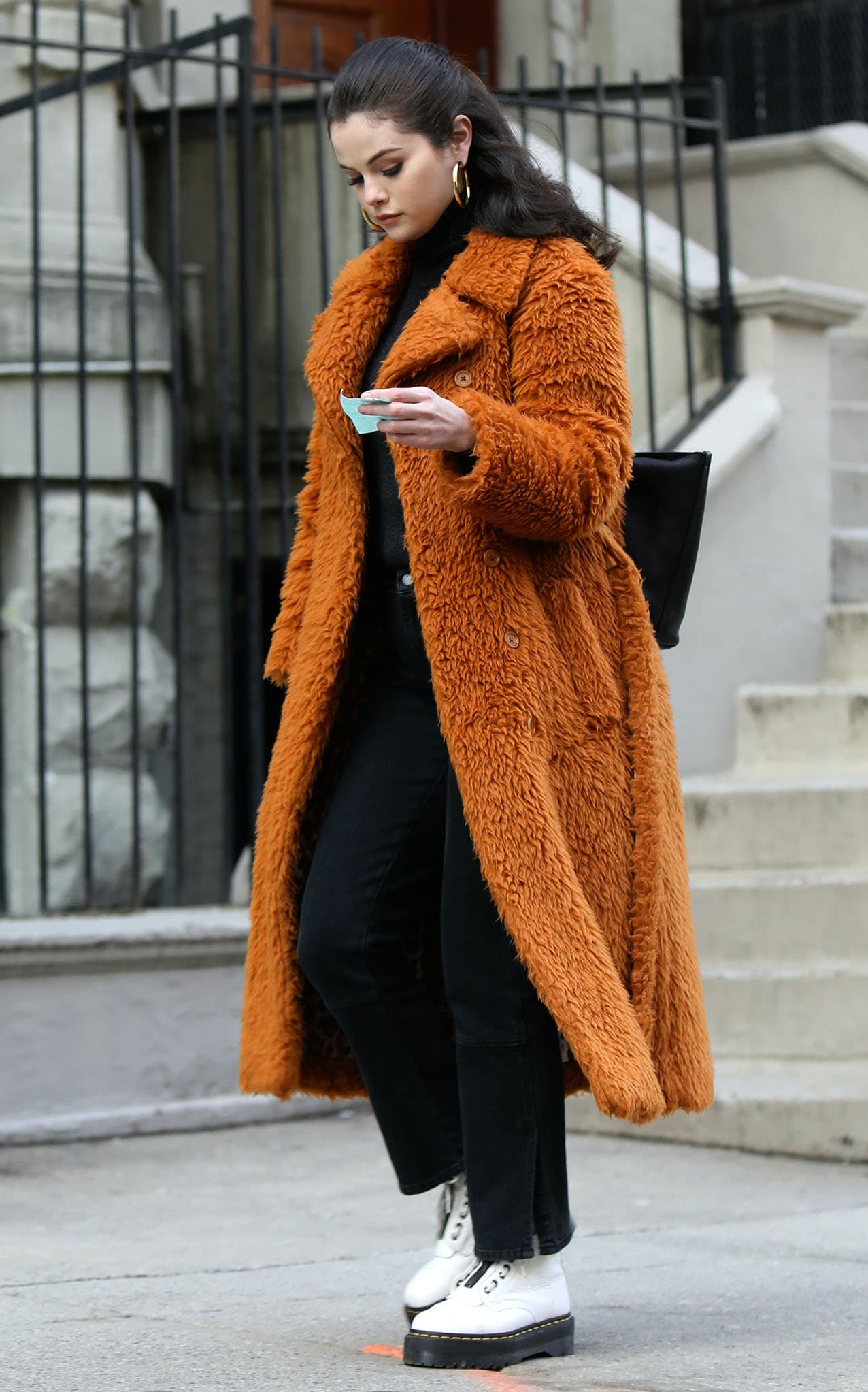 A closer street-style moment highlights how the oversized faux-fur texture contrasts with the clean, structured silhouette of her white platform boots and flared black denim