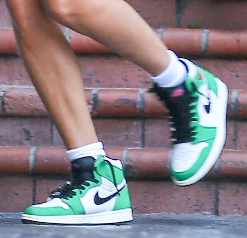 A close-up highlights Hailey Bieber’s Air Jordan 1 Retro High OG “Lucky Green” sneakers, distinguished by vivid green leather overlays, black Swooshes, and classic white panels