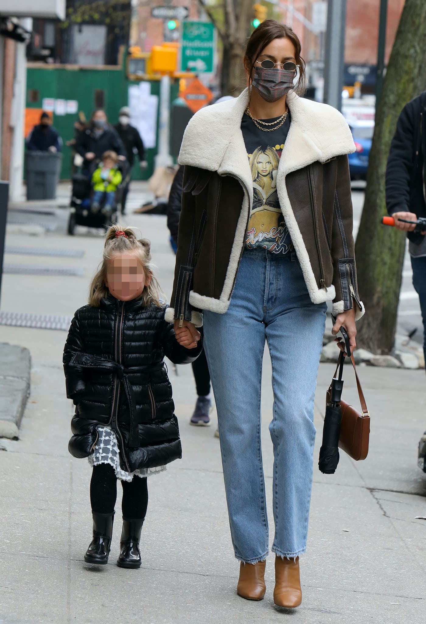 Irina Shayk walks through New York City's Greenwich Village with her daughter, Lea de Seine, wearing a vintage Britney Spears T-shirt, a Yulia Wave shearling aviator jacket, Rolla's straight-leg jeans, and retro-inspired tan square-toe leather boots