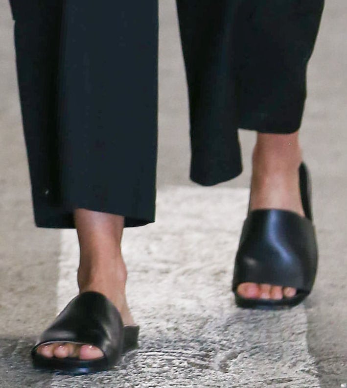 Jessica Alba finishes her relaxed look with minimalist black leather slide sandals, adding a sleek touch to her casual-chic ensemble