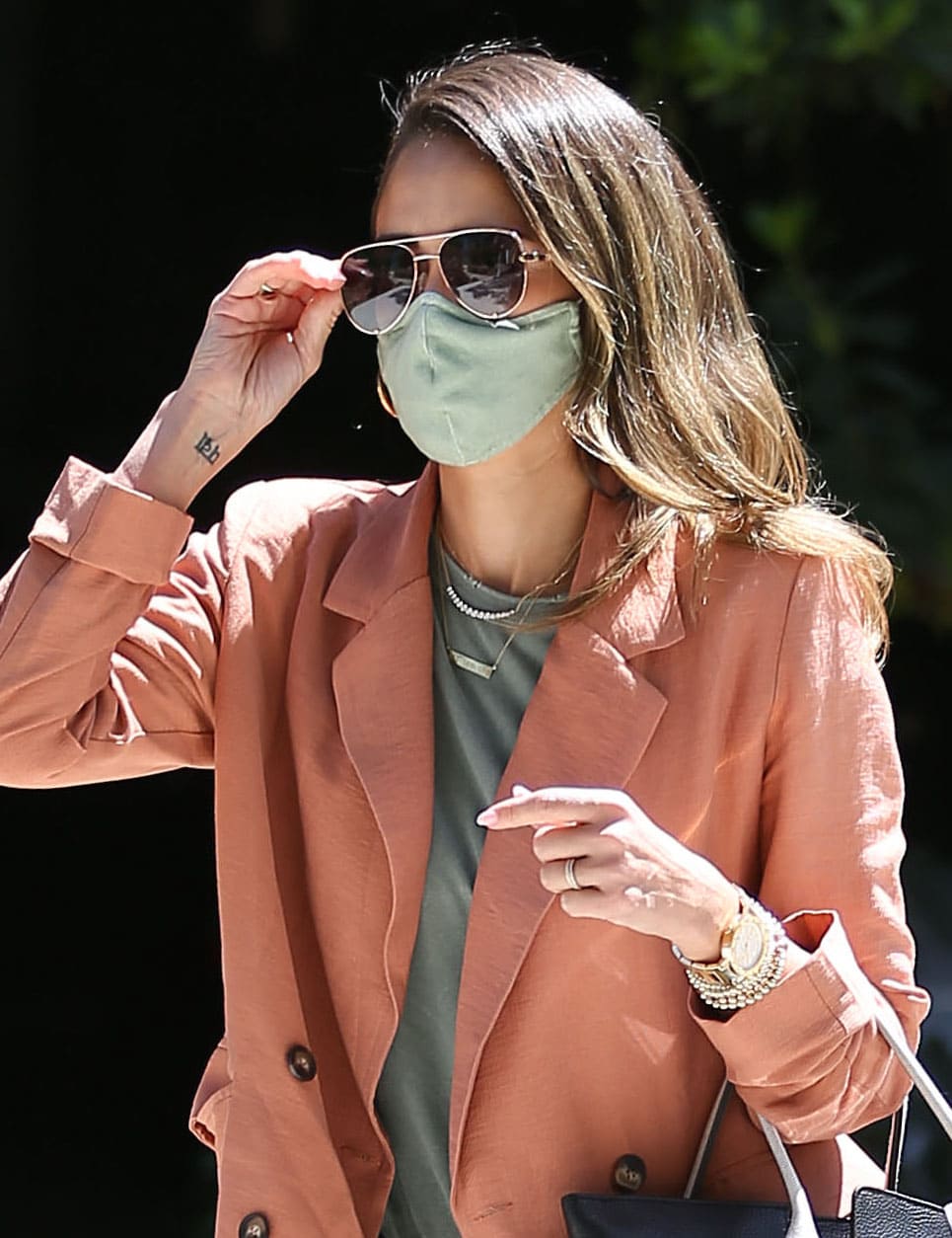 Jessica Alba accessorizes her spring office look with layered gold jewelry, aviator sunglasses, and a coordinated green face mask