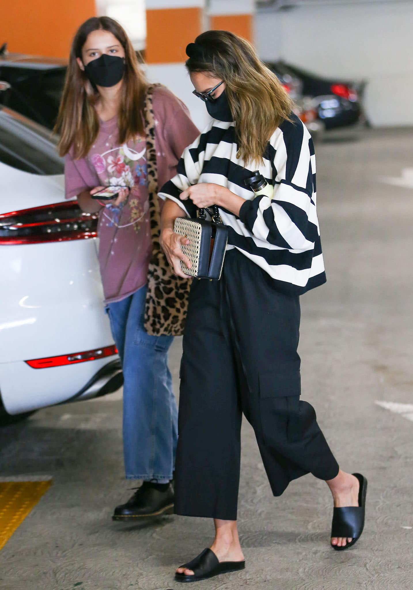Jessica Alba goes casual-chic in a black-and-white striped Rebecca Minkoff sweatshirt, cropped cargo pants, and leather slide sandals while grocery shopping in Los Angeles with her daughter Honor Marie on March 30, 2021