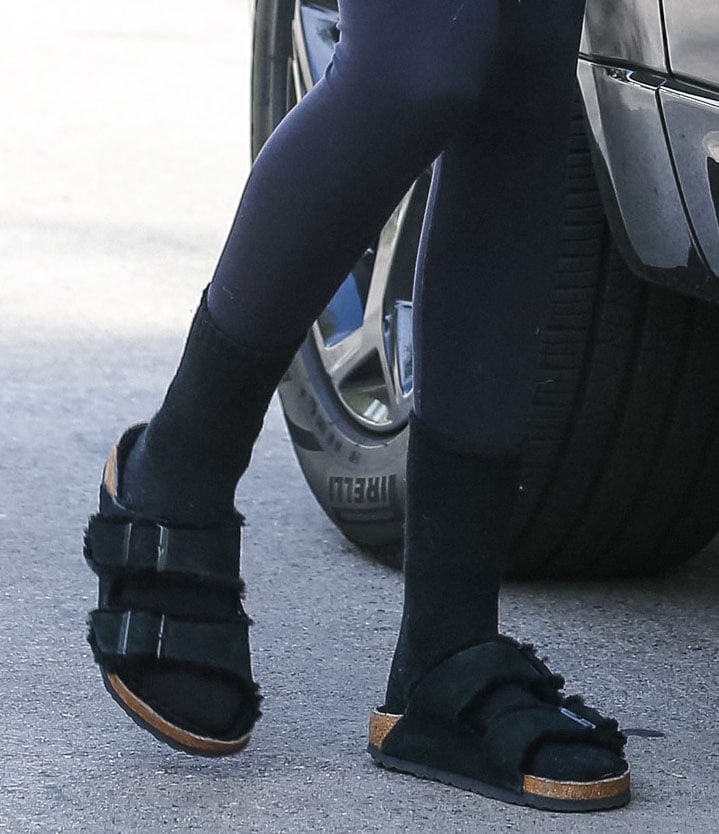 Kaia Gerber grounds her off-duty look in black Birkenstock “Arizona” shearling sandals, pairing the plush, fur-lined footbed with socks for a cozy take on the model-approved staple