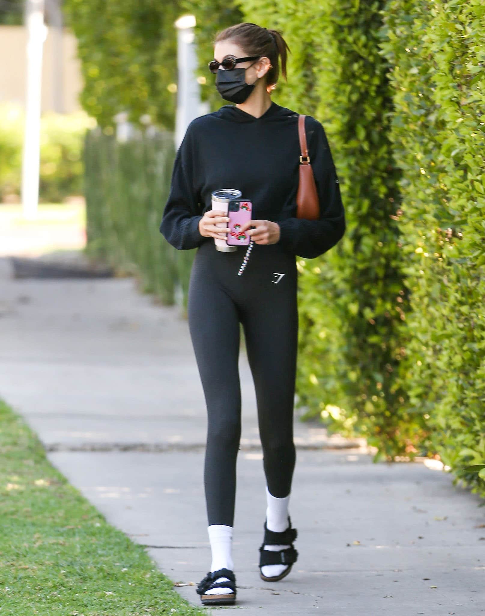 Kaia Gerber steps out in shearling-lined Birkenstock “Arizona” sandals, pairing the cozy staple with white crew socks, Gymshark leggings, and an Alo Yoga hoodie for a model-off-duty uniform