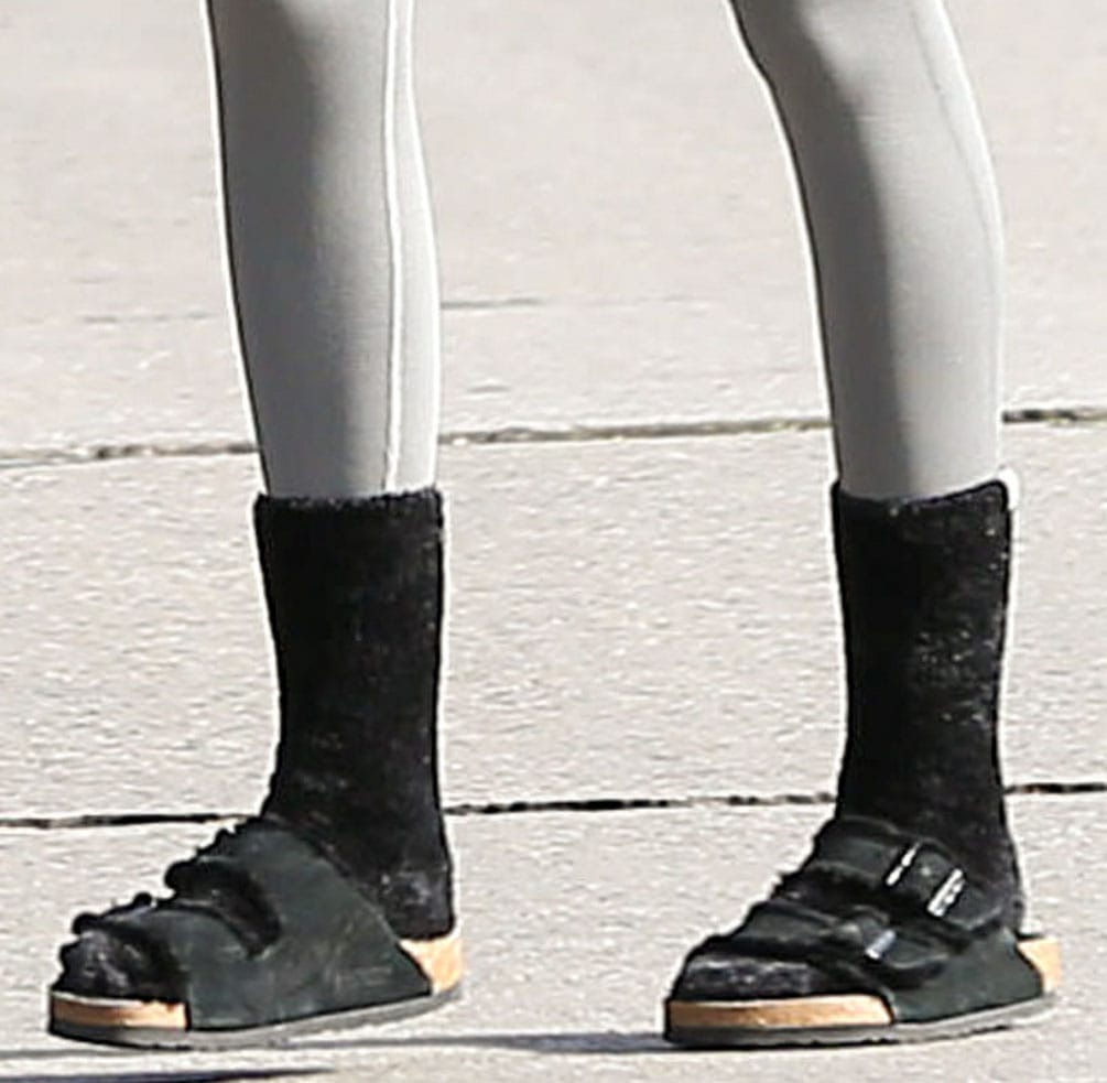 Kaia Gerber grounds her relaxed Pilates outfit with black UGG Leda cozy socks and Birkenstock Arizona shearling sandals featuring the brand’s signature cork footbed and double-buckle straps