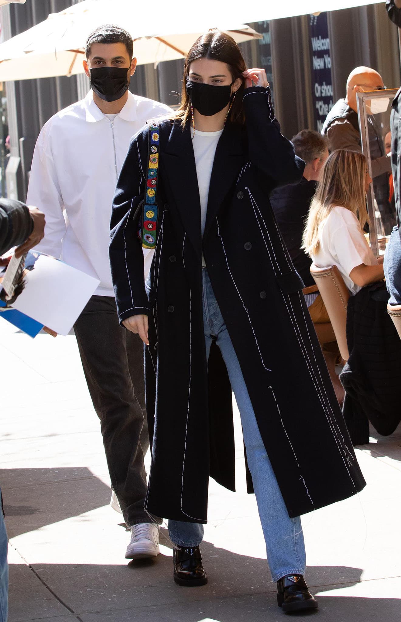 Kendall Jenner grounds her understated off-duty look—black tailored coat, white tee, and straight-leg jeans—with chunky black leather loafers, proving how polished flats can anchor casual street style with quiet authority