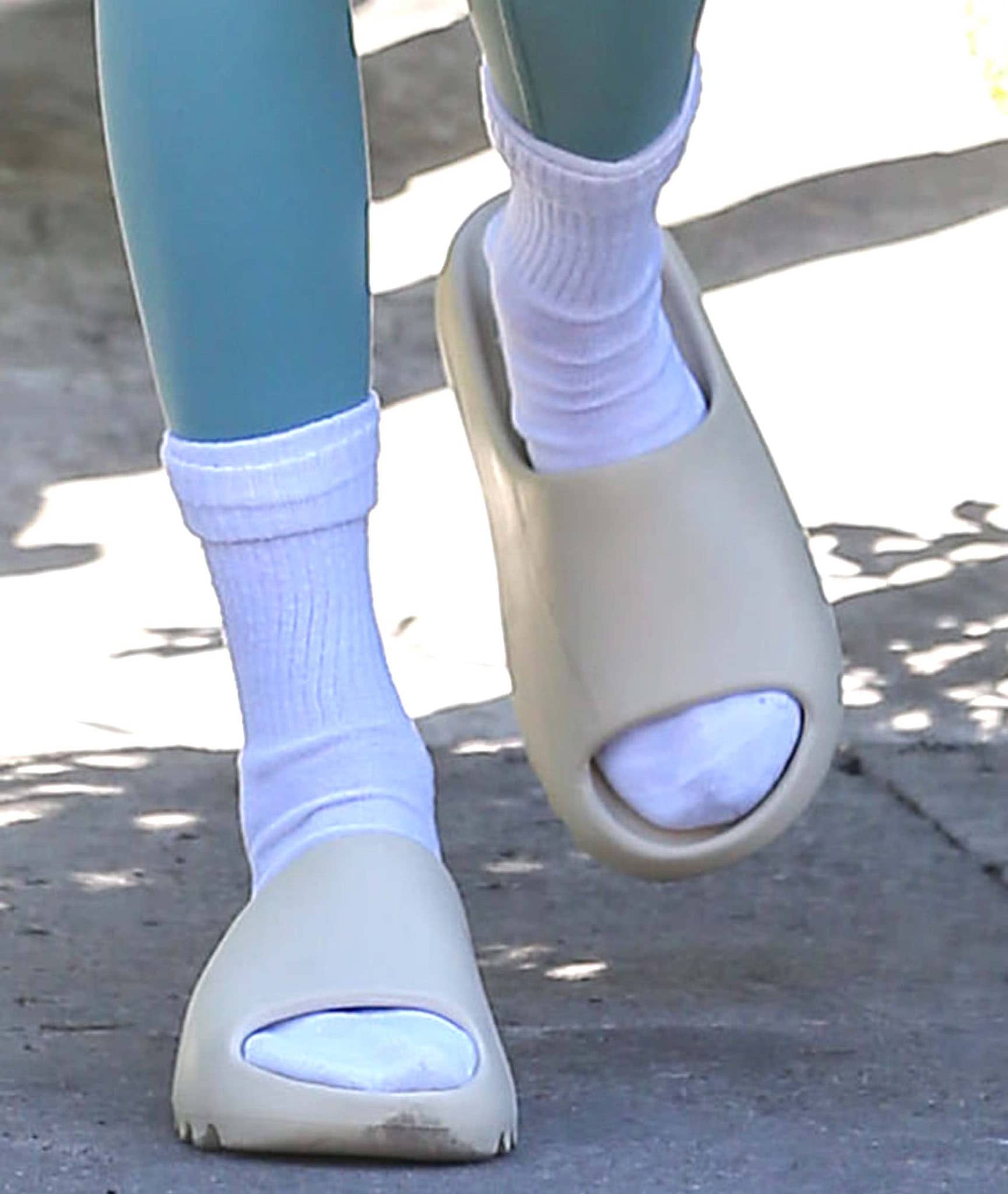 Kendall Jenner pairs classic white crew socks with Yeezy Slides in the sleek Bone colorway