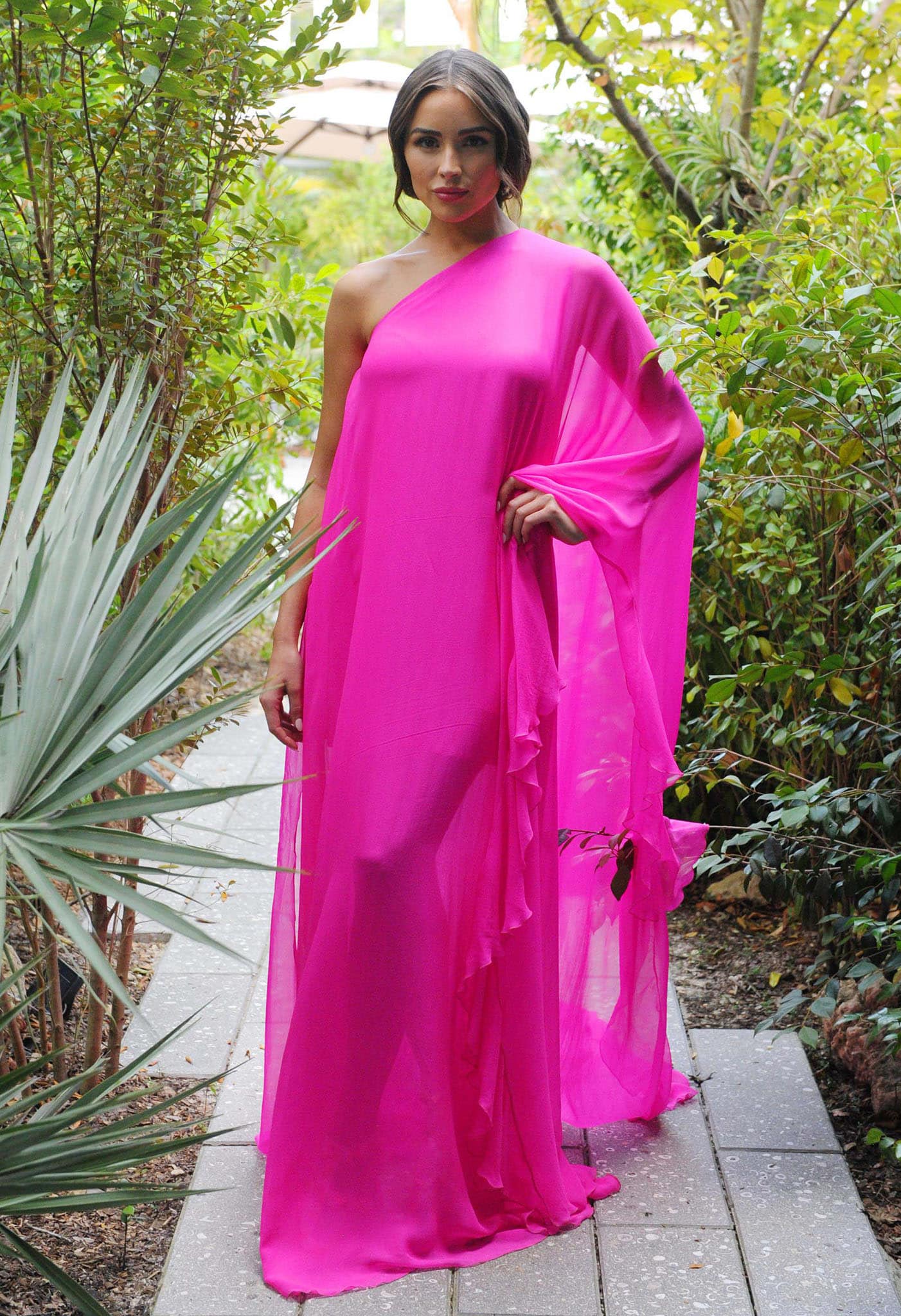Olivia Culpo showcases the flowing one-shoulder silhouette and dramatic draping of her fuchsia Valentino Spring 2021 silk-chiffon gown
