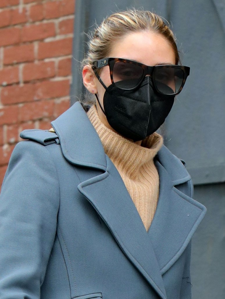 Olivia Palermo wears oversized tortoiseshell sunglasses, a black face mask, and her hair in a bun with a Smythe coat
