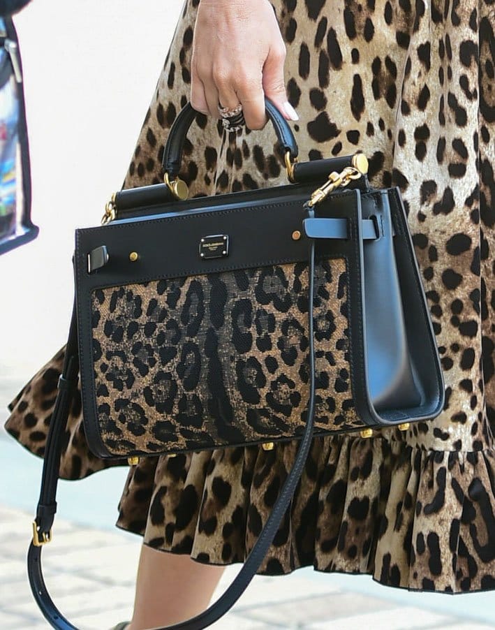 Sofia Vergara carries a structured Dolce Gabbana Sicily 62 handbag in matching leopard print with black leather trim and gold-tone hardware alongside her ruffled animal-print dress