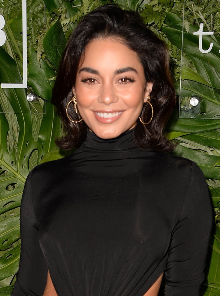 Vanessa Hudgens accentuates her features with peachy blush and lipstick, complemented by a shoulder-length wavy hairstyle with subtle volume