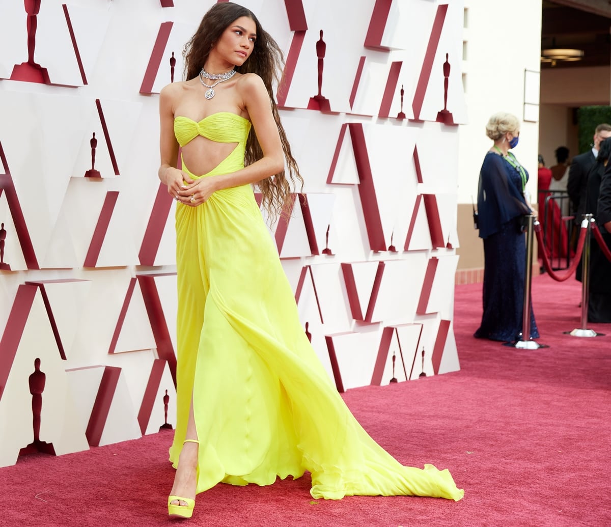 Zendaya stuns at the 2021 Oscars in a neon yellow Valentino cutout gown, perfectly paired with matching Jimmy Choo platform heels for a bold, monochromatic look