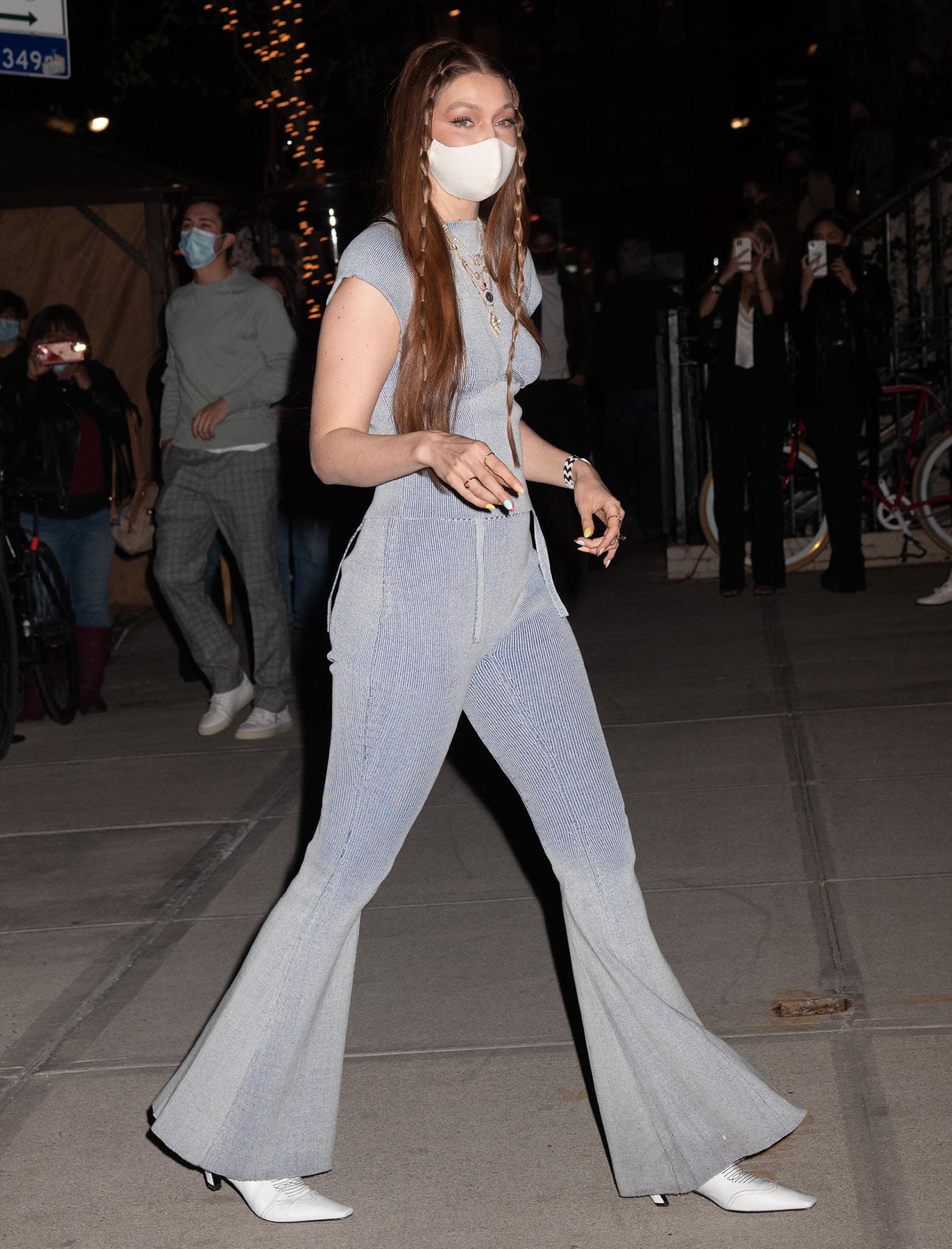 The exaggerated bell-bottom proportions draw the eye straight to Gigi’s pointed white Khaite Dallas Western boots as she walks through New York City
