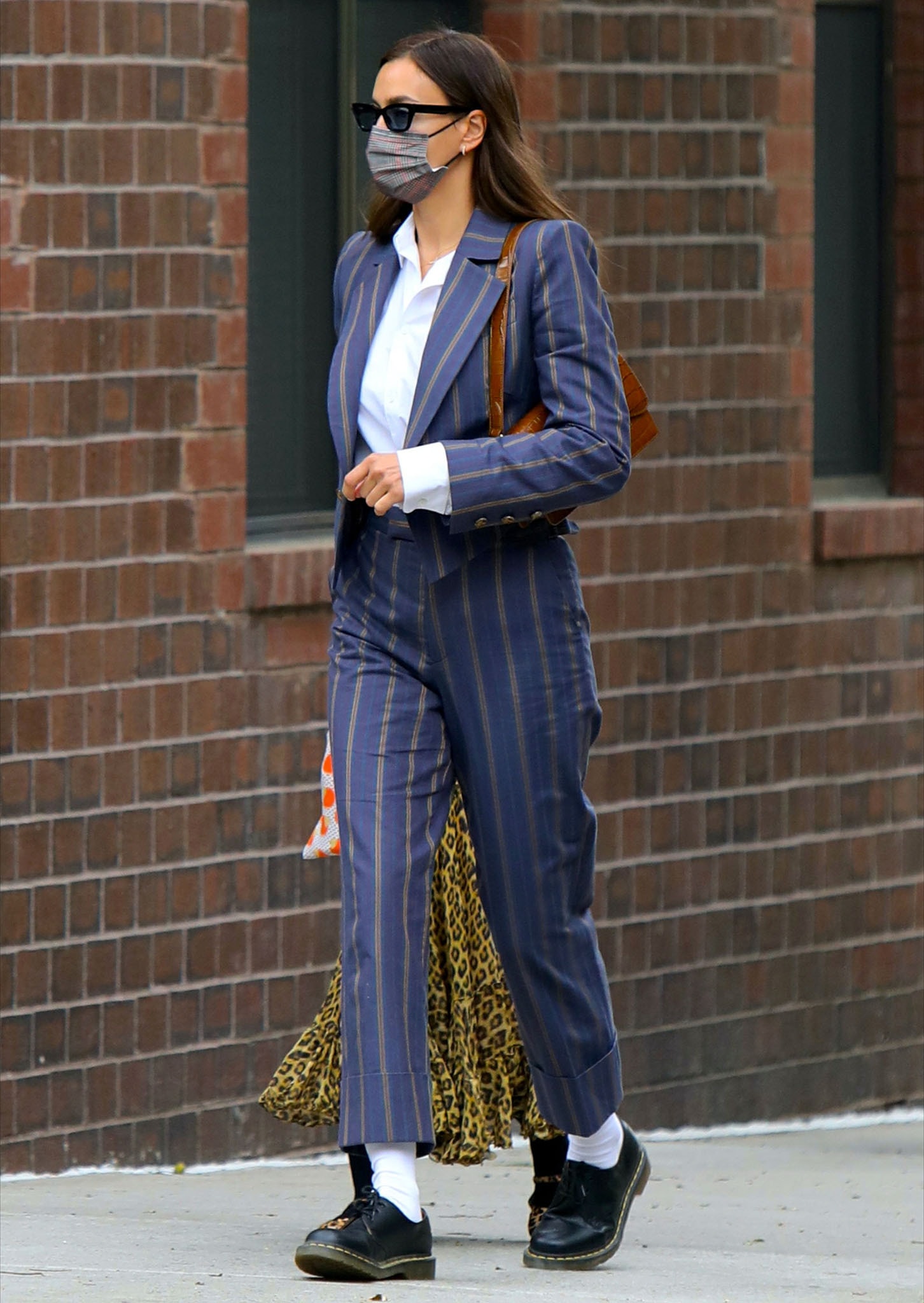 Irina Shayk keeps her tailoring directional in a cropped pinstripe suit, letting the low-profile 1461s and bright socks define the look’s edge