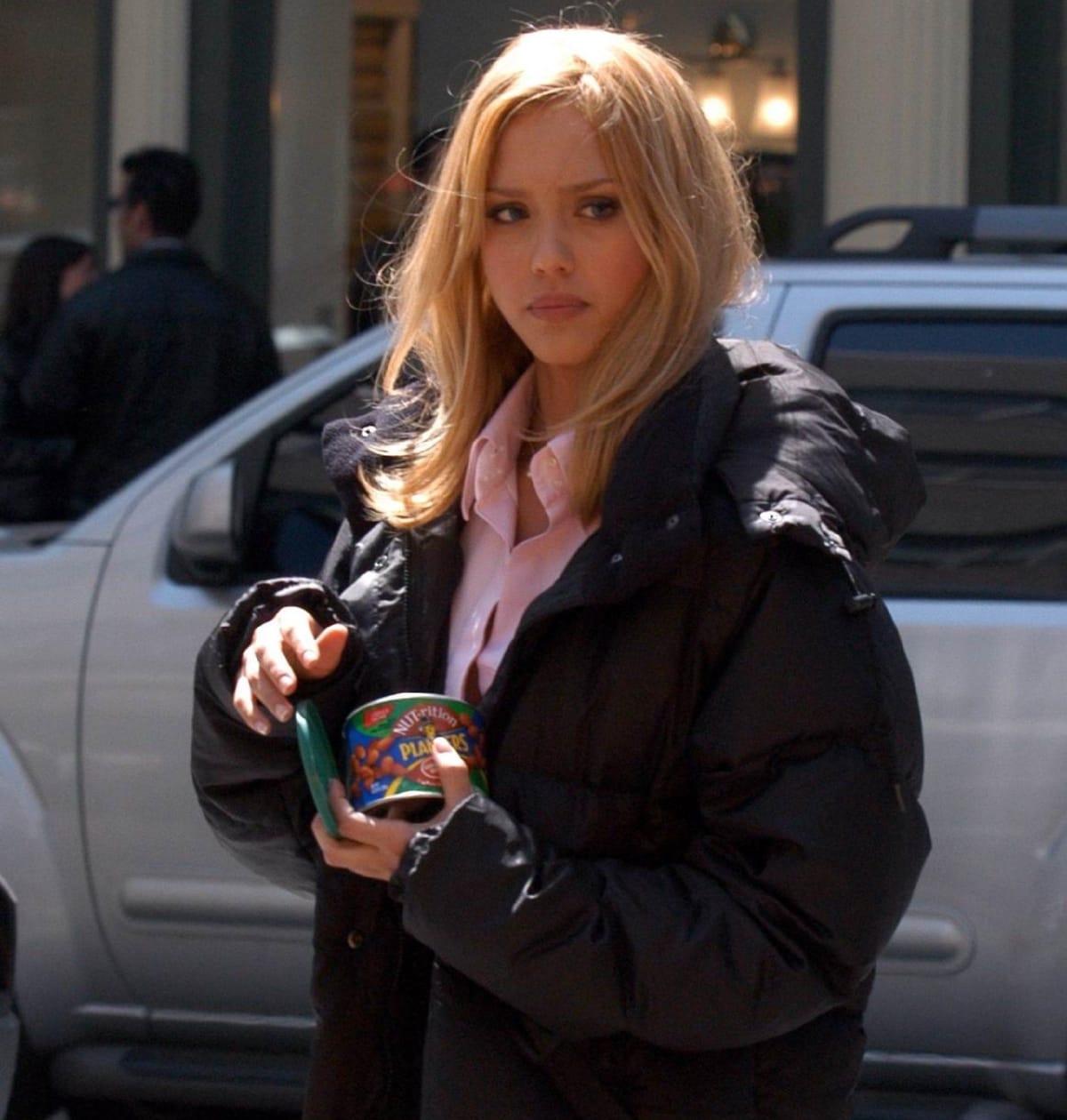 Jessica Alba takes a break on the New York set of Fantastic Four in 2005, keeping warm in a black puffer jacket while snacking between scenes