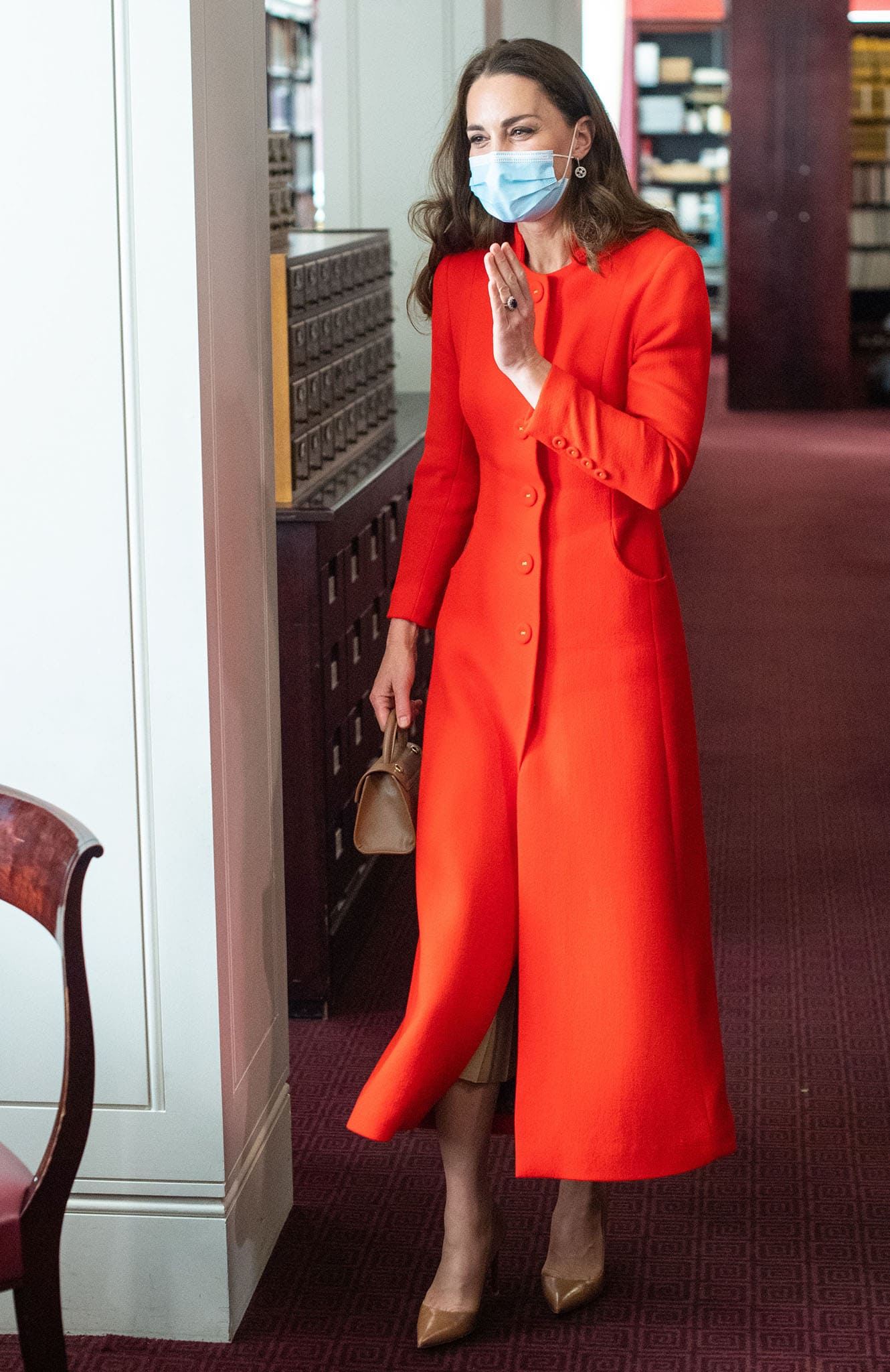 Kate Middleton elevates her vibrant Eponine red wool coat dress with a flowing Zara pleated midi skirt, brown Ralph Lauren "Celia" pumps, and a coordinating Demellier Nano Montreal bag during the Hold Still launch at the National Portrait Gallery