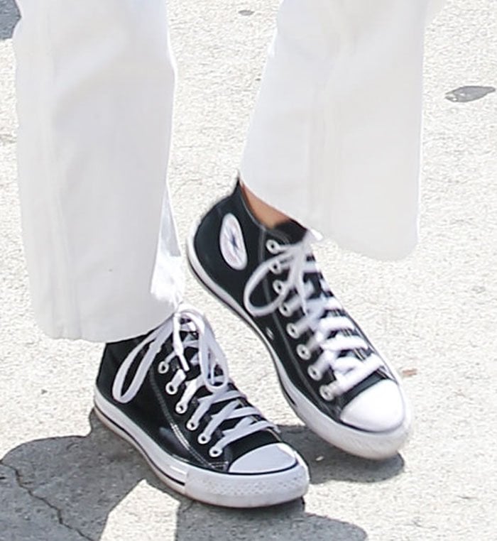 Kendall Jenner keeps the look grounded with classic black-and-white Converse Chuck Taylor All-Star high-top sneakers, pairing the timeless canvas shoes with crisp white straight-leg jeans