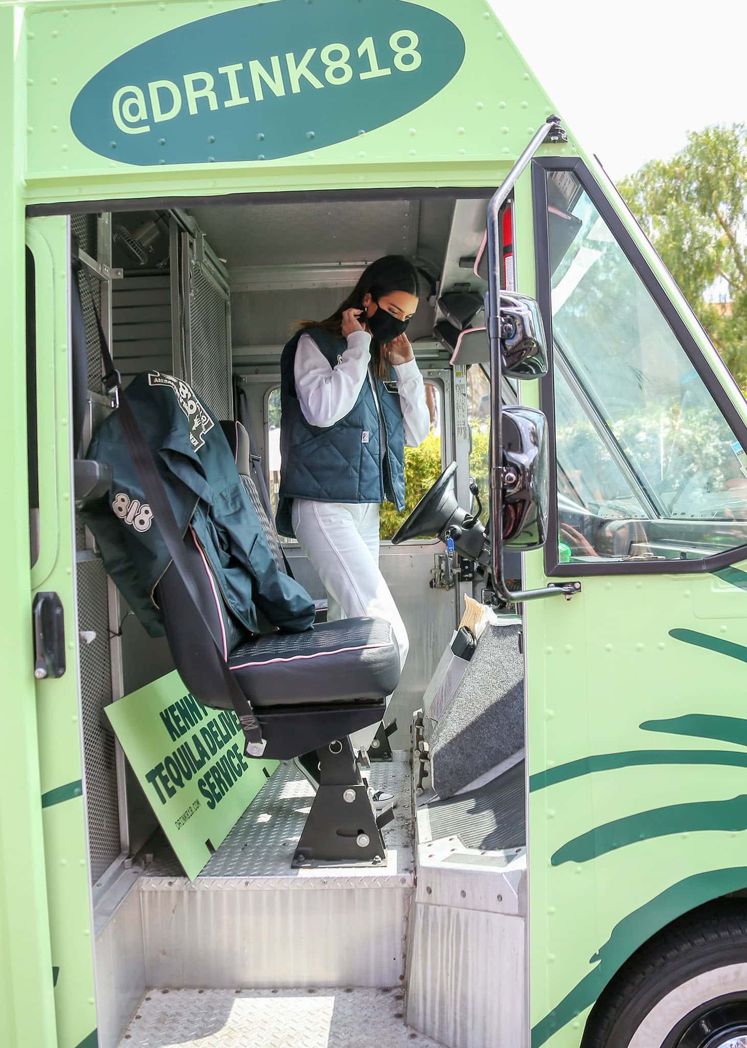 Kendall Jenner steps out of her custom 818 Tequila delivery truck in Los Angeles on May 17, 2021, pairing a quilted branded vest and white straight-leg jeans with classic black-and-white Converse Chuck Taylor All-Star high-top sneakers