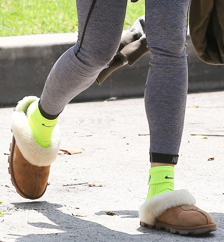 Sofia Boutella added a playful flash of color to her Pilates look with neon green Nike socks styled inside chestnut UGG Coquette slippers trimmed in plush white sheepskin