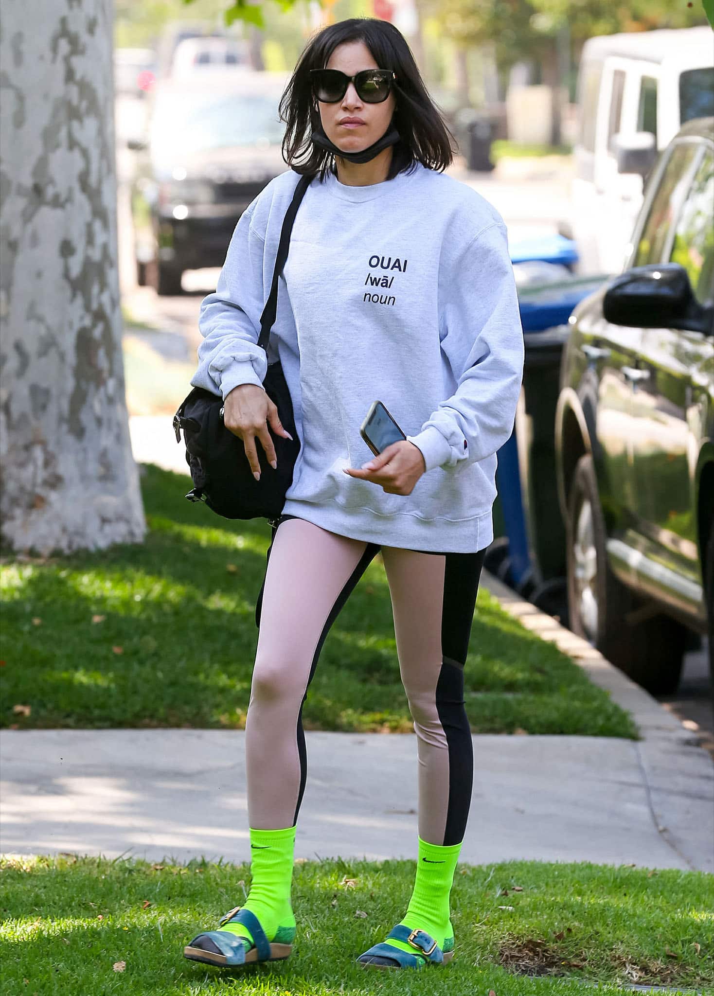 Sofia Boutella mixed neon green Nike socks with blue buckle sandals, balancing the bold color pop against a slouchy gray sweatshirt and two-tone leggings for another dancer-inspired Pilates look on May 5, 2021