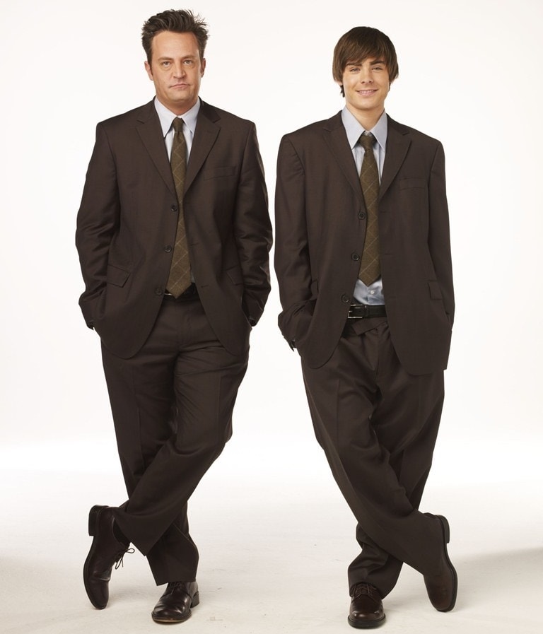 In 17 Again, Zac Efron and Matthew Perry embody the same character across time, both suited up in matching brown tailored ensembles with coordinated ties and polished leather dress shoes that underscore the film’s generational mirror theme