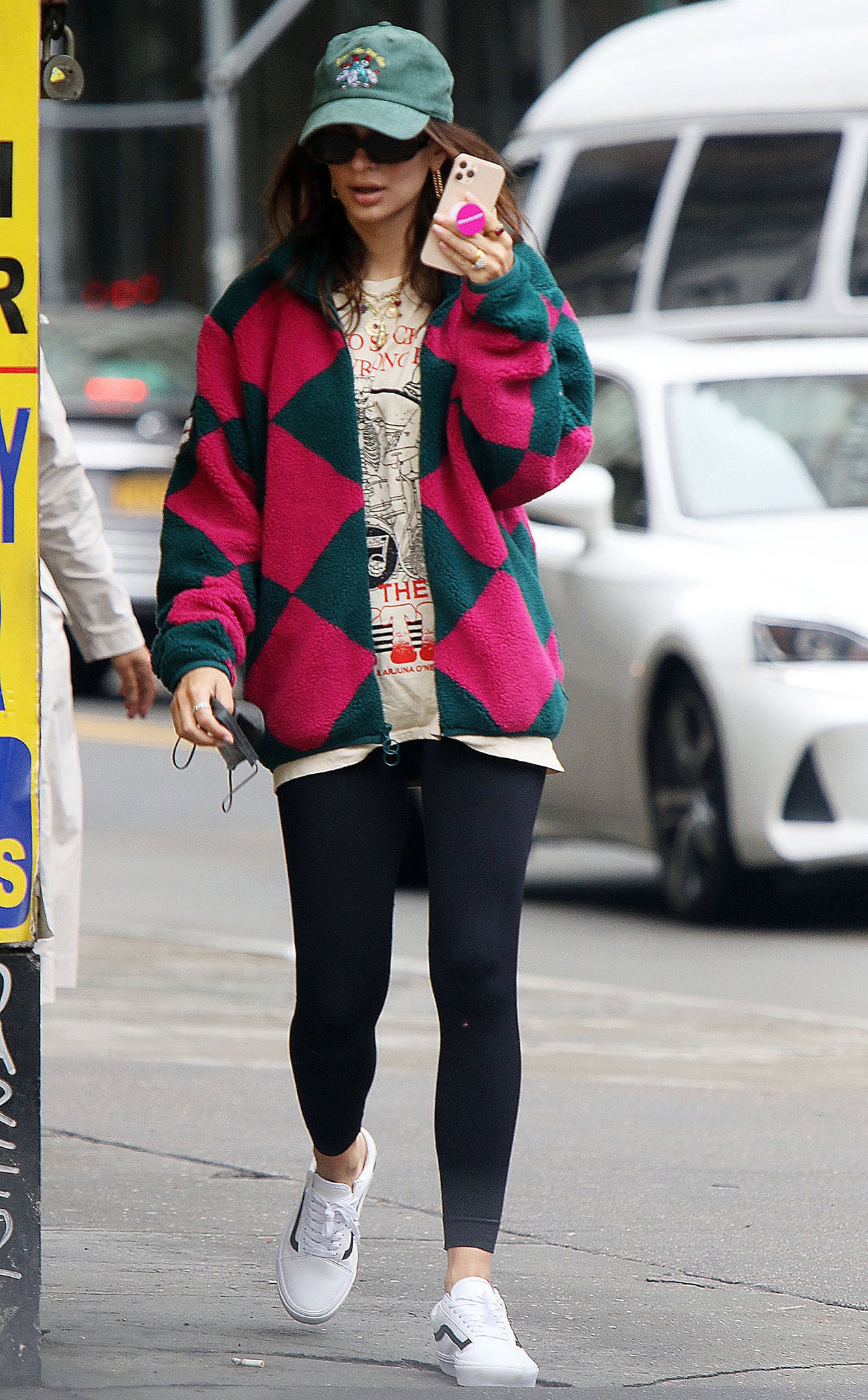 Anchoring the bold harlequin fleece and graphic tee, her clean white Vans Old Skool sneakers ground the look with a crisp, skate-rooted minimalism that keeps the outfit effortlessly wearable