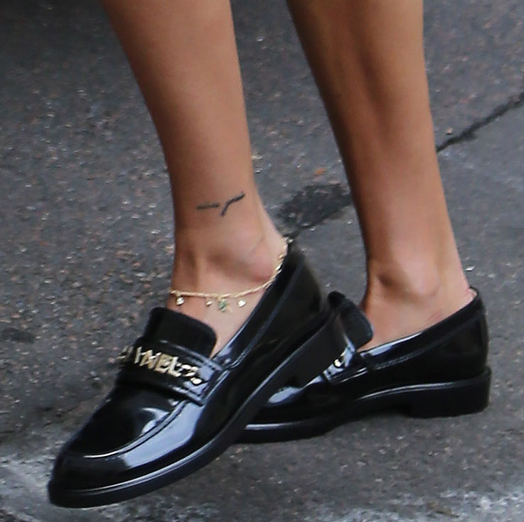 Hailey Bieber finishes her monochromatic lilac look with glossy black Chanel loafers featuring the house's signature gold logo hardware