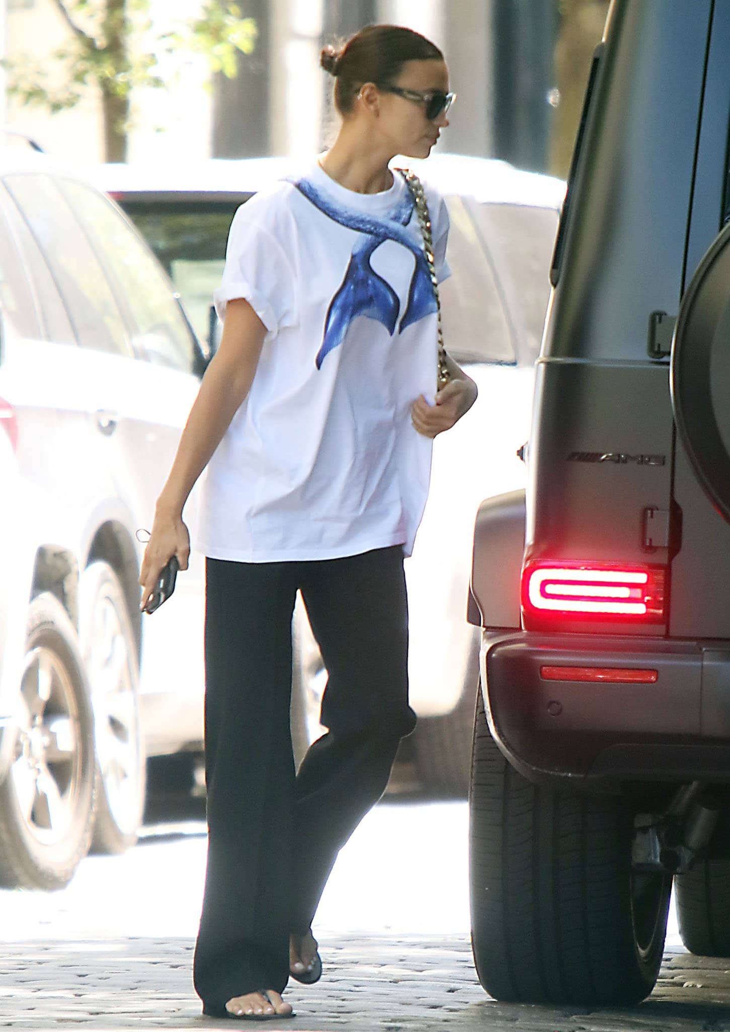 Irina Shayk balanced the oversized Burberry mermaid-print tee with fluid black trousers and minimalist thong sandals, creating an understated Soho look built on relaxed proportions.