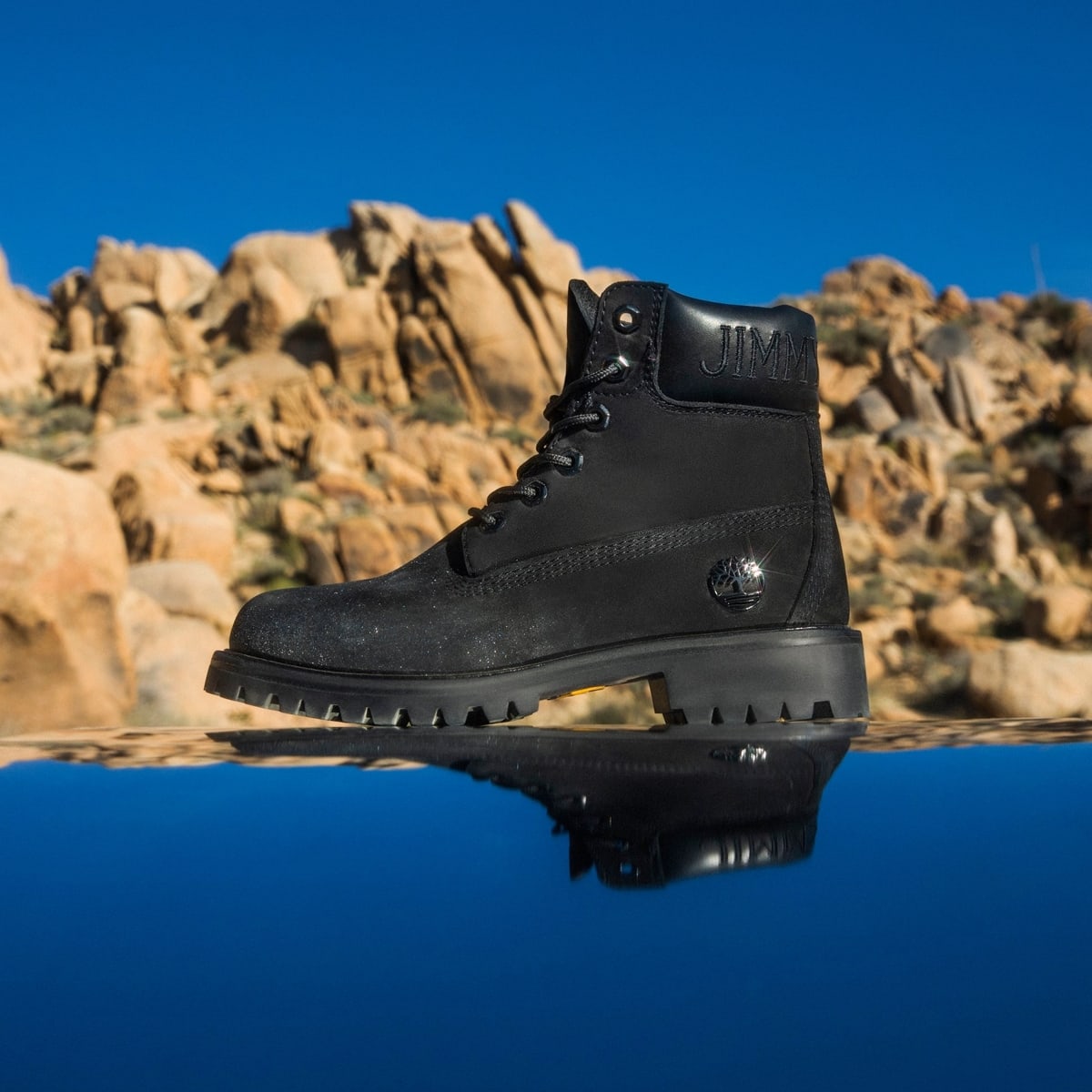 The black Jimmy Choo × Timberland boot offers a sleek, tonal alternative, finished with subtle shimmer and embossed branding for a more understated luxury look