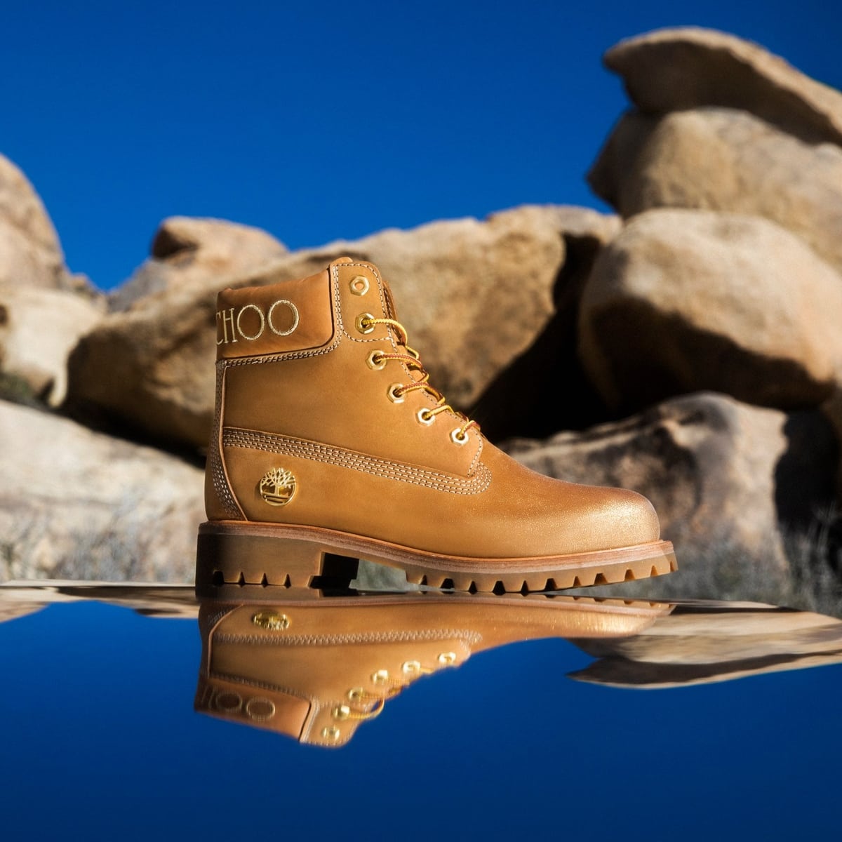 The Jimmy Choo × Timberland wheat nubuck boot is photographed against a rugged desert backdrop, highlighting its luxe leather finish and elevated take on the iconic 6-inch silhouette