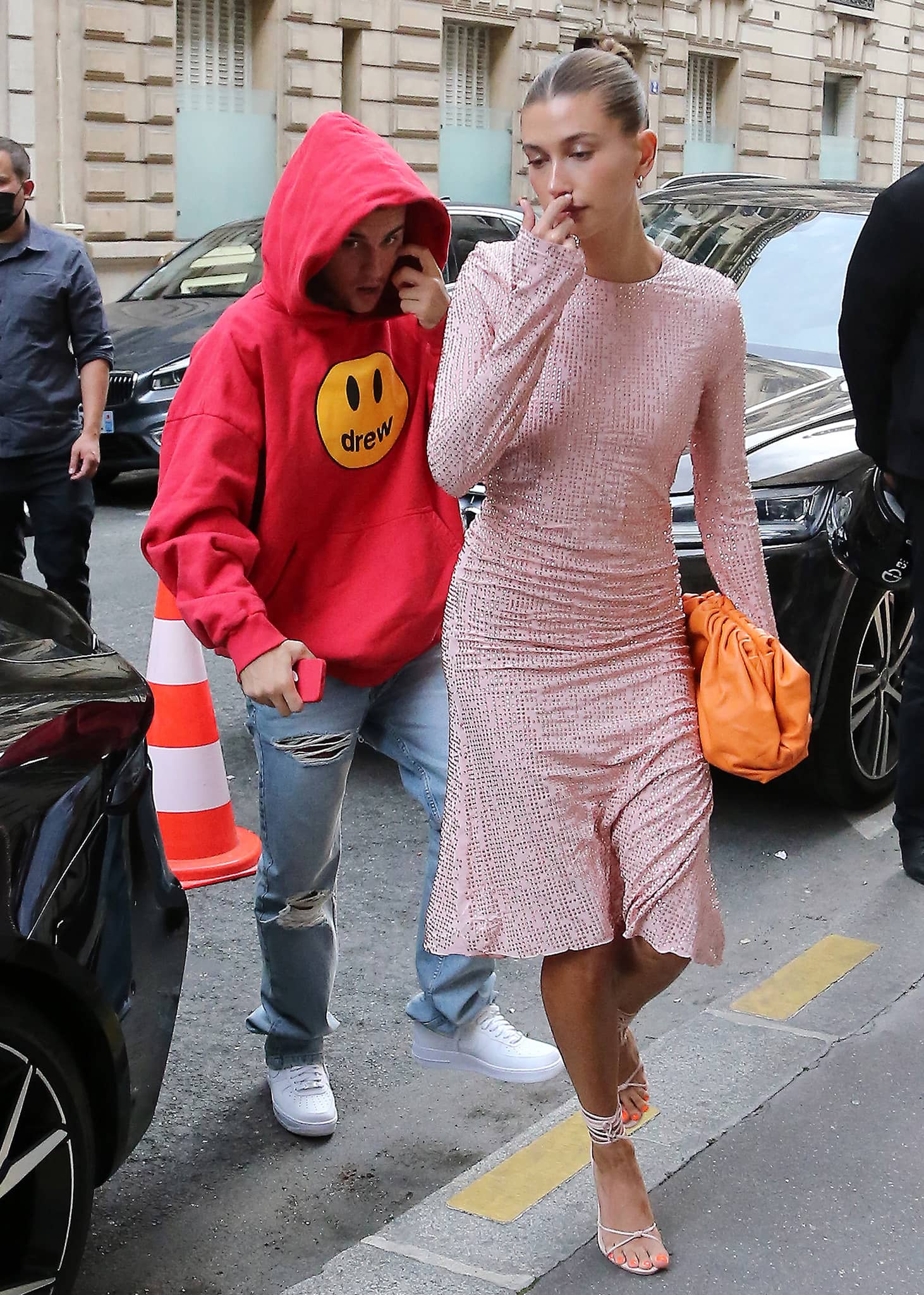 Hailey Bieber arrives for dinner at Stresa in Paris on June 21, 2021, wearing a crystal-embellished Miu Miu dress with lace-up Femme Athens sandals, while Justin Bieber keeps it casual in a red Drew hoodie and white Nike Air Force 1 sneakers