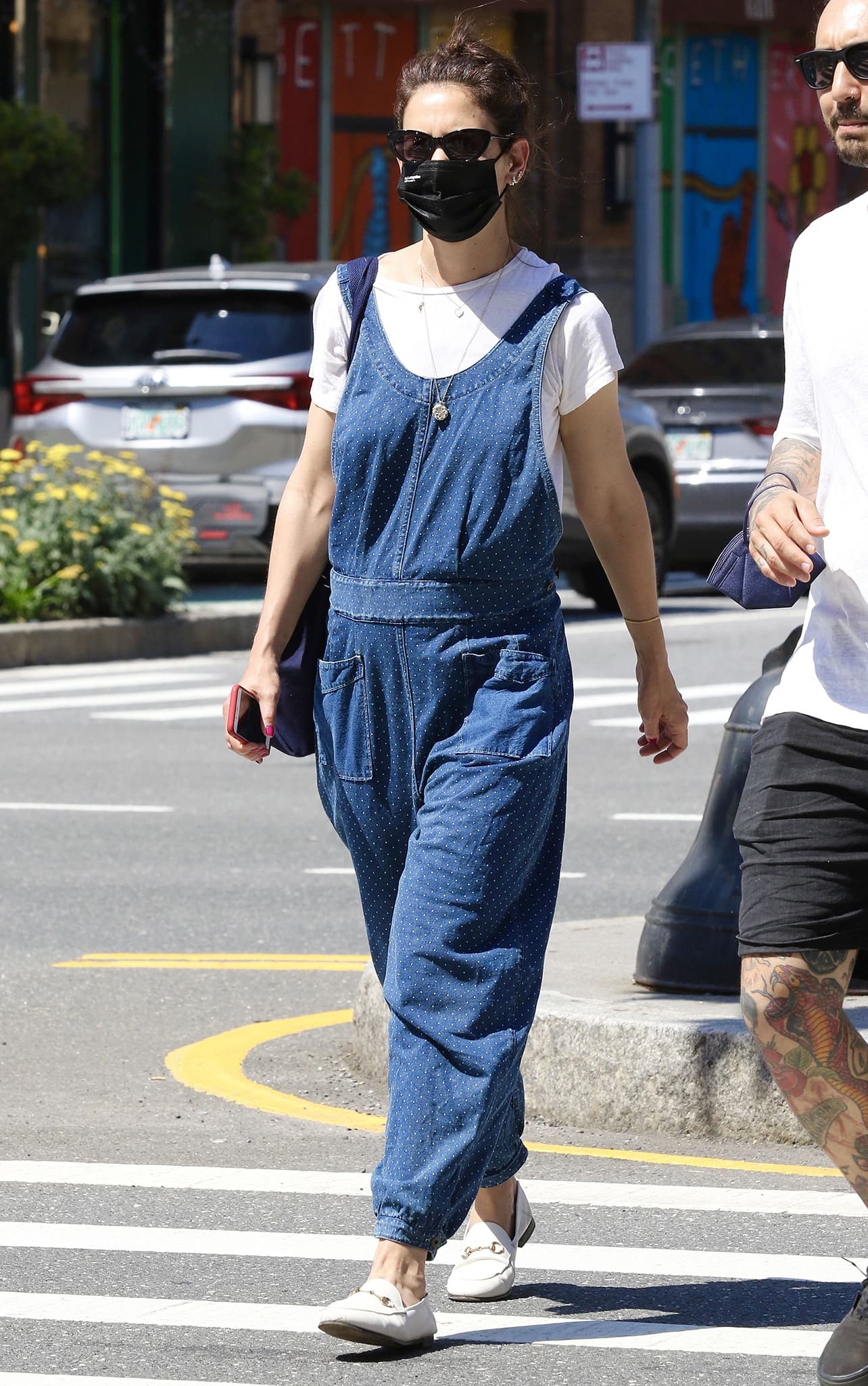 Katie Holmes leans into relaxed, bohemian ease in polka-dot denim overalls layered over a crisp white tee, grounding the look with white Gucci Brixton horsebit loafers that add polished structure to her off-duty New York stride
