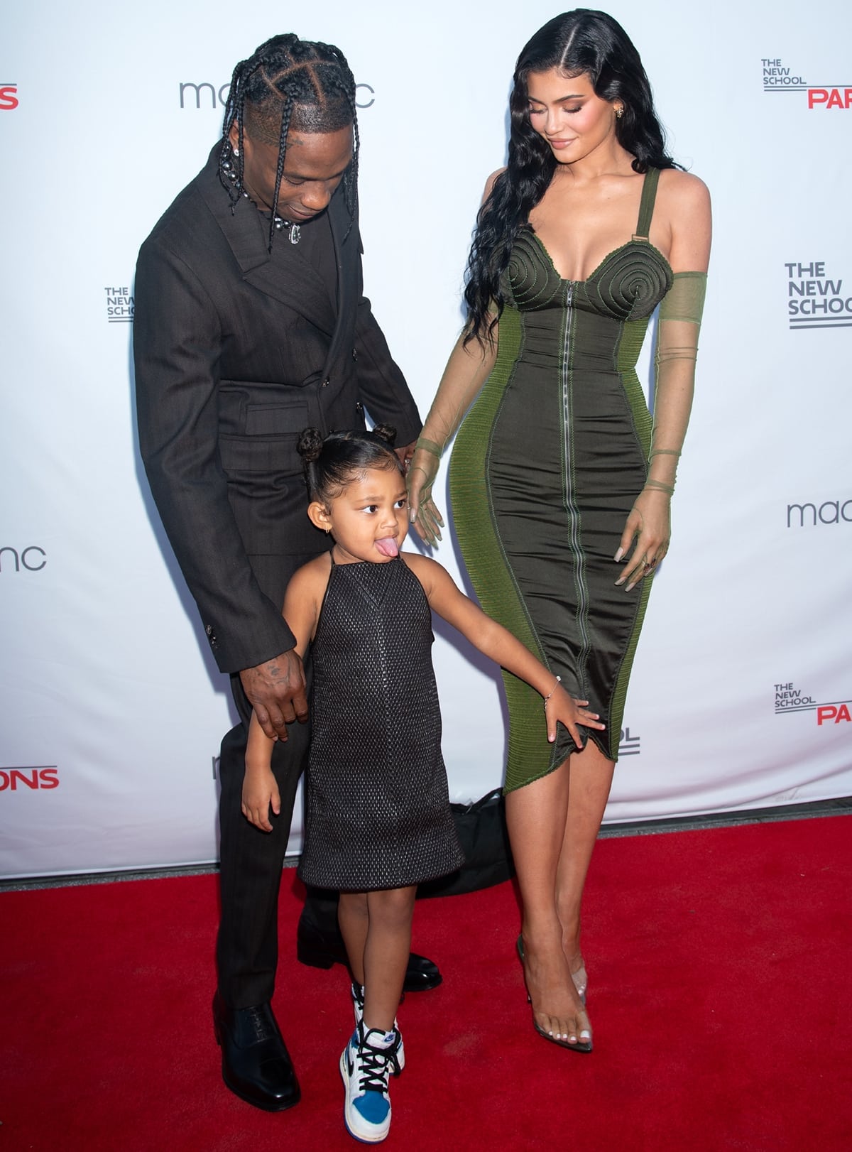 Stormi Webster wears pre-release Travis Scott x Fragment Design x Air Jordan 1 Retro High sneakers alongside Kylie Jenner and Travis Scott at the 2021 Parsons Benefit