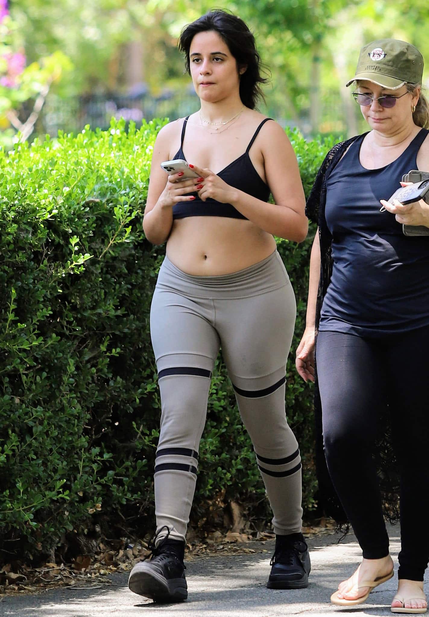 Camila Cabello steps out in a black Alo Yoga “Delight” bralette and two-tone “Legit” leggings, finishing the relaxed workout look with chunky black sneakers and layered gold necklaces during a walk in Los Angeles