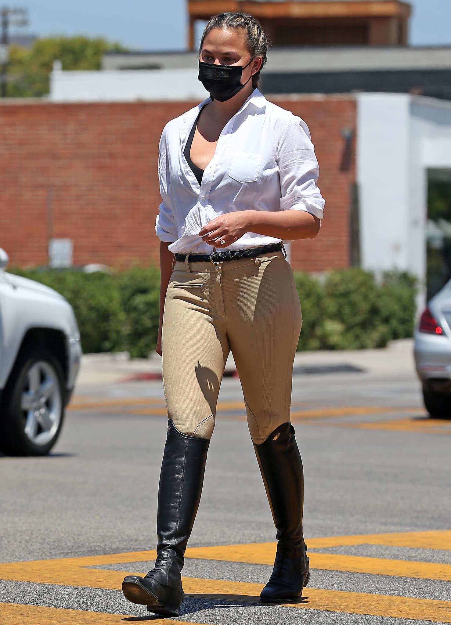 Chrissy Teigen opts for an equestrian-inspired outfit with Frank Eileen white shirt, Tuffrider pants, and Isabel Marant belt