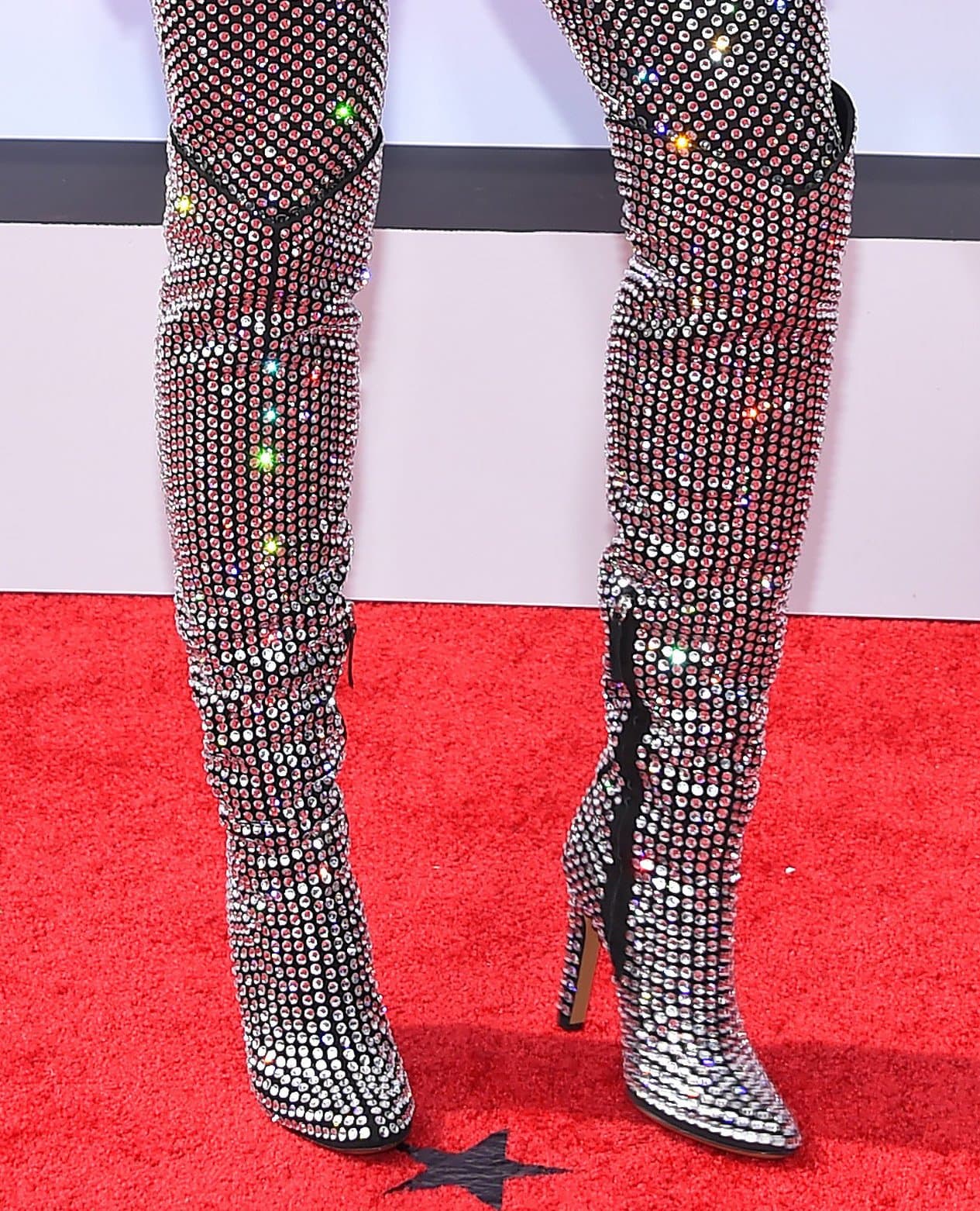 Ciara completes her disco-inspired look with crystal-embellished thigh-high boots featuring sleek pointed toes and towering stiletto heels, adding maximum sparkle