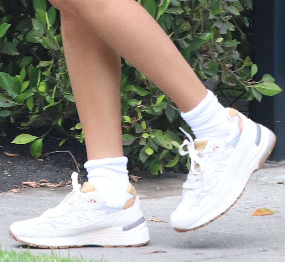 Close up, Hailey’s New Balance 992 sneakers reveal a layered mix of mesh and suede with a cushioned sole, grounding the look in retro performance design