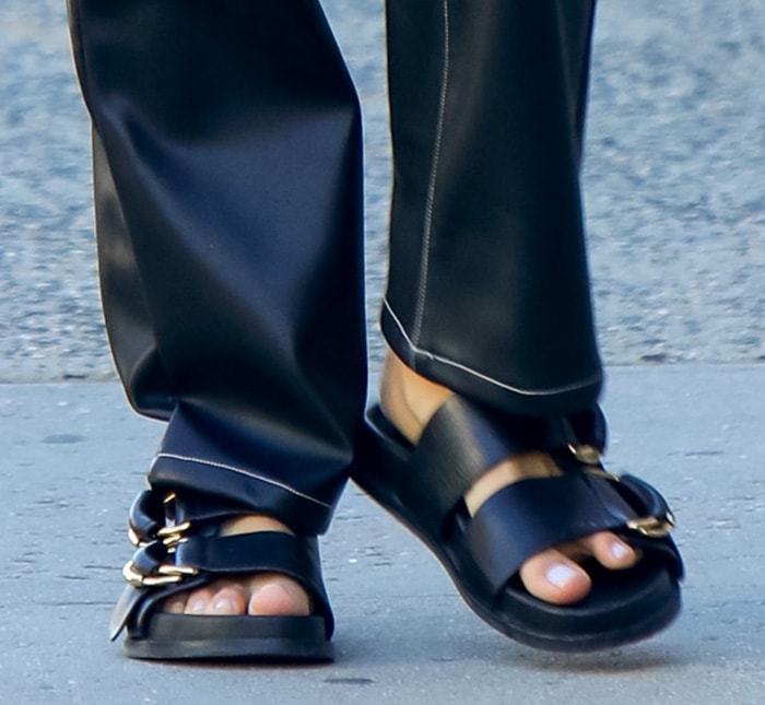 Irina Shayk finishes her black leather pants with chunky two-strap flatform sandals, using the bold buckles and thick soles to give the streamlined look a grounded, utilitarian edge