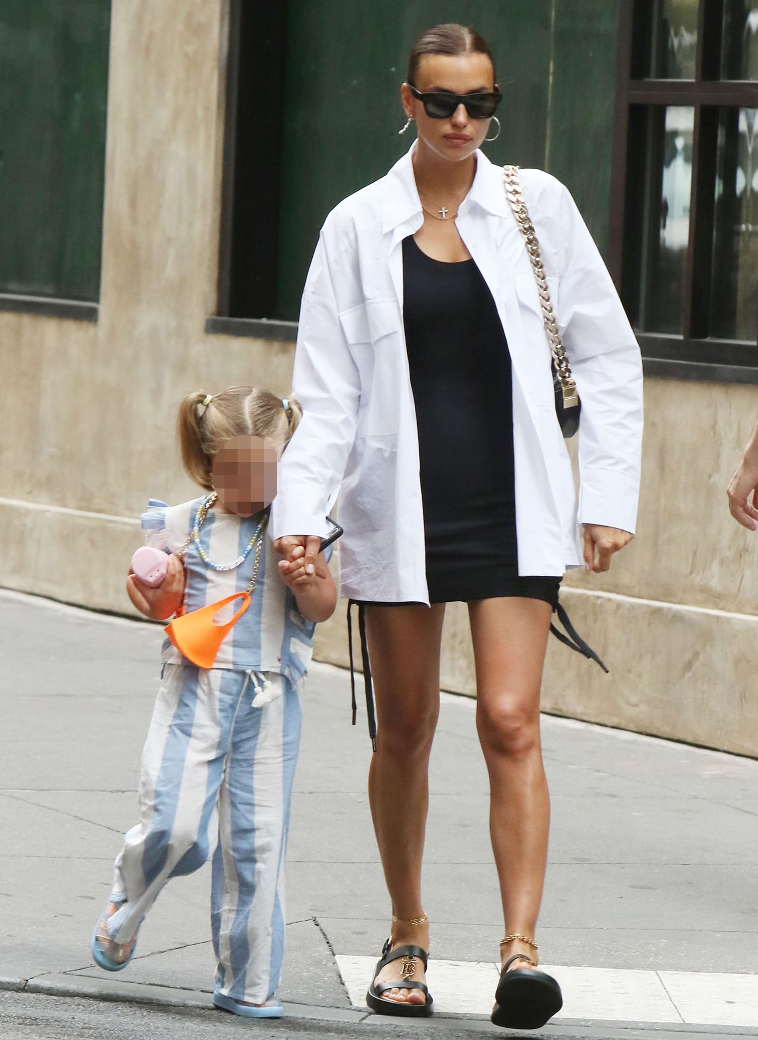 Irina Shayk steps out in Soho on June 22, 2021, pairing a black mini dress with an oversized white button-down and chunky sandals as she walks hand in hand with her daughter