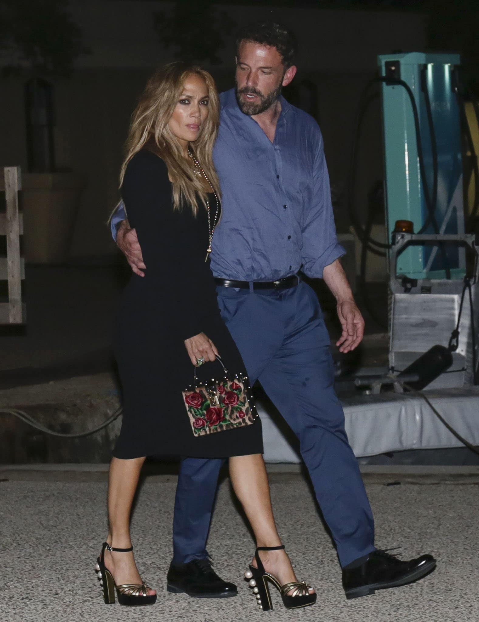 Jennifer Lopez turned heads in a form-fitting black Dolce Gabbana dress paired with pearl-embellished platform heels and a rose-embroidered velvet box bag, while Ben Affleck kept it classic in a blue button-down shirt, navy trousers, and polished black dress shoes