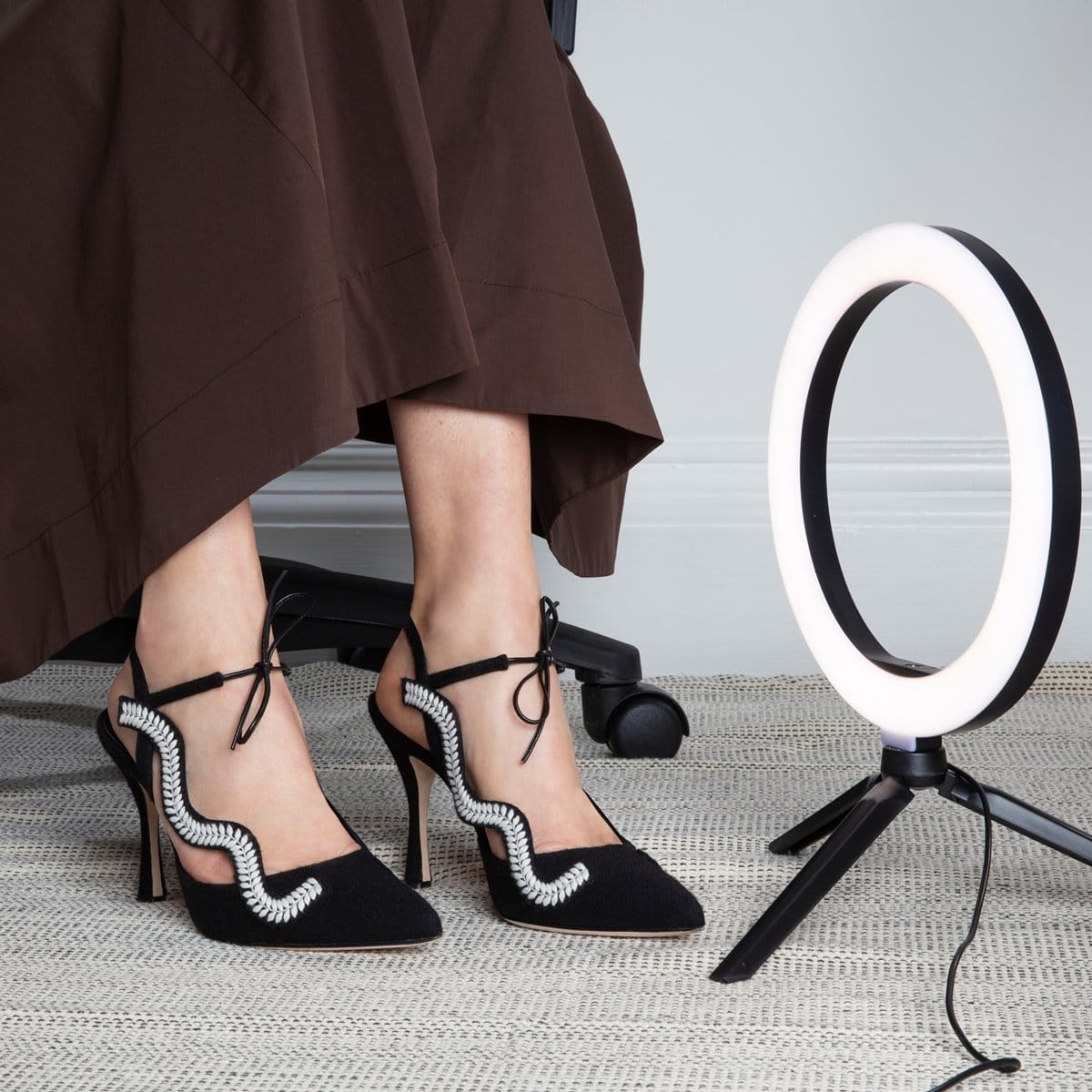 Manolo Blahnik's black wool pointed-toe Waga pumps feature white embroidery detail, an elasticated slingback strap, and a kid leather lace-up front strap