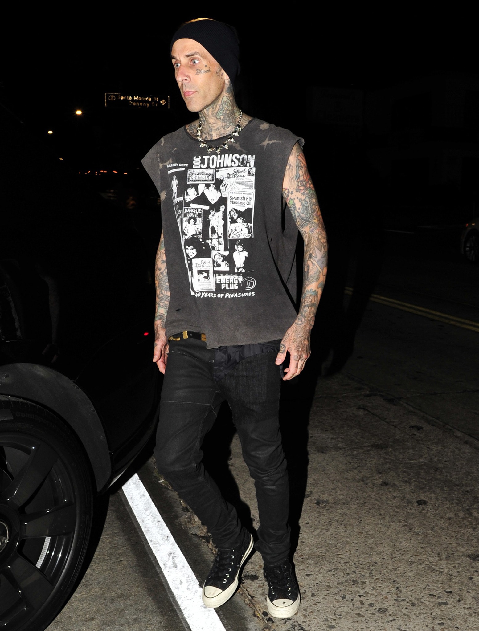 Travis Barker stayed true to his signature punk aesthetic in a distressed graphic muscle tee, black denim, classic canvas sneakers, and a minimalist black beanie