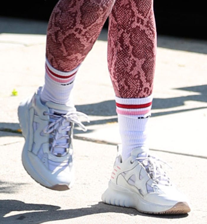 Vanessa Hudgens grounds her pink snakeskin leggings with Mercer Amsterdam Jupiter sneakers, pairing the chunky white trainers with striped crew socks for a sporty athleisure finish