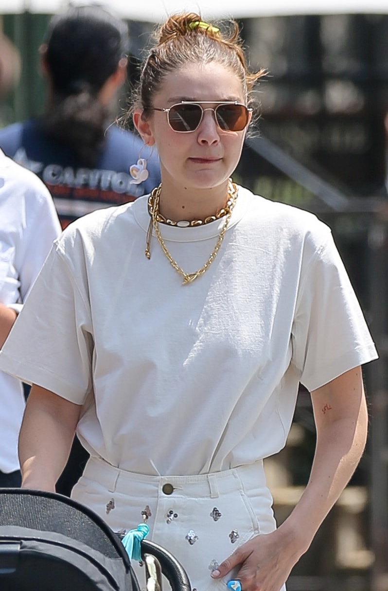 Layered gold jewelry, geometric sunglasses, and a relaxed cream tee give Gigi Hadid's off-duty look a polished yet understated feel