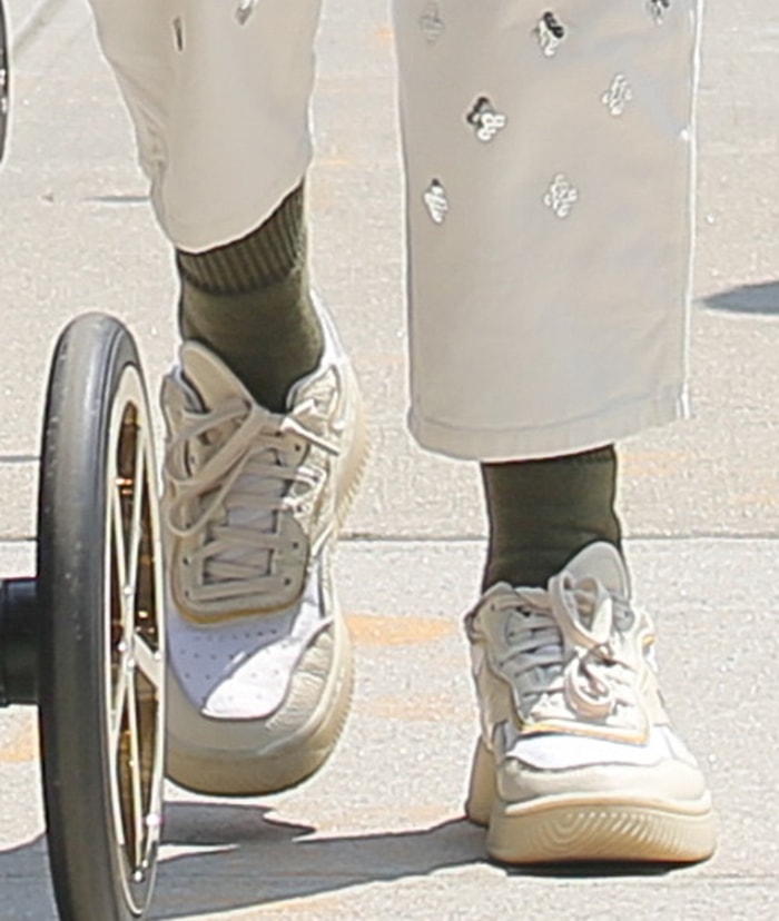 Olive-green socks add an unexpected contrast to Gigi Hadid's cream-and-white palette, drawing attention to her retro-inspired Reebok sneakers