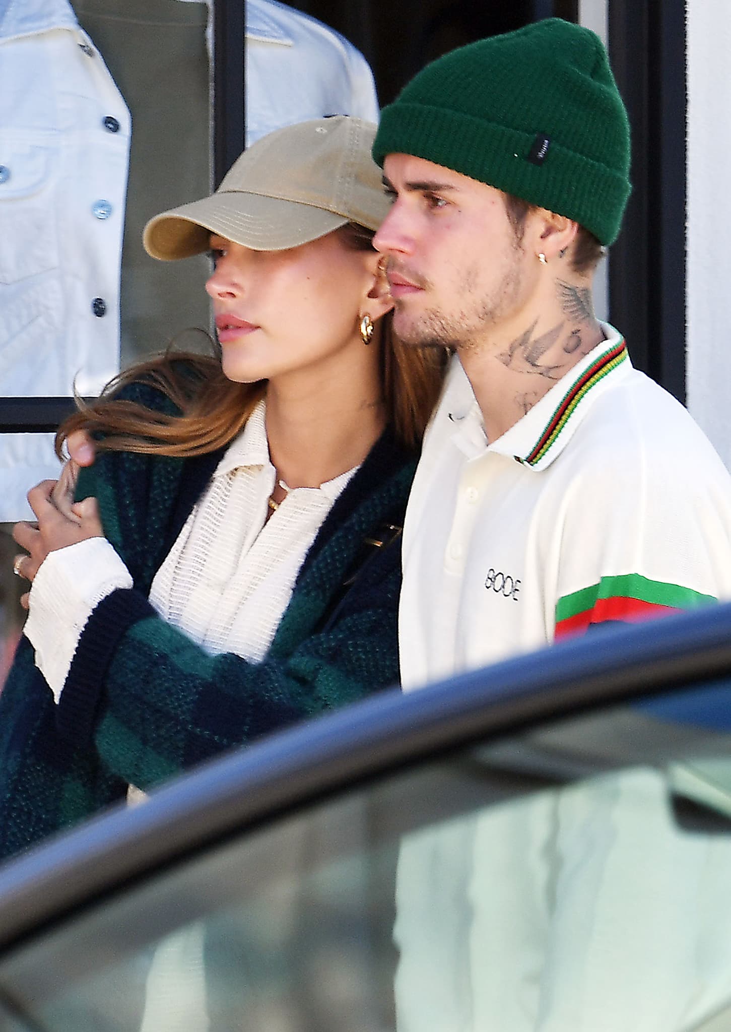 Hailey Bieber wearing a beige baseball cap and Jennifer Fisher gold hoop earrings beside Justin Bieber